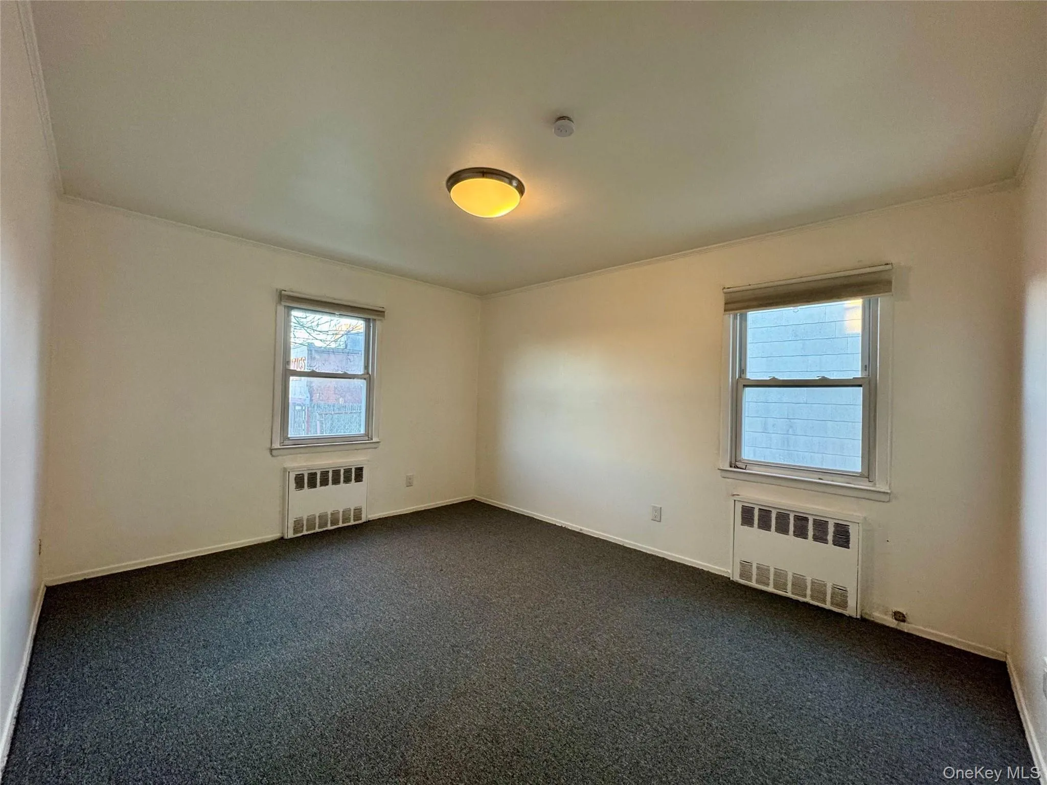 Empty room with radiator heating unit and dark carpet Empty room with radiator heating unit and dark carpet
