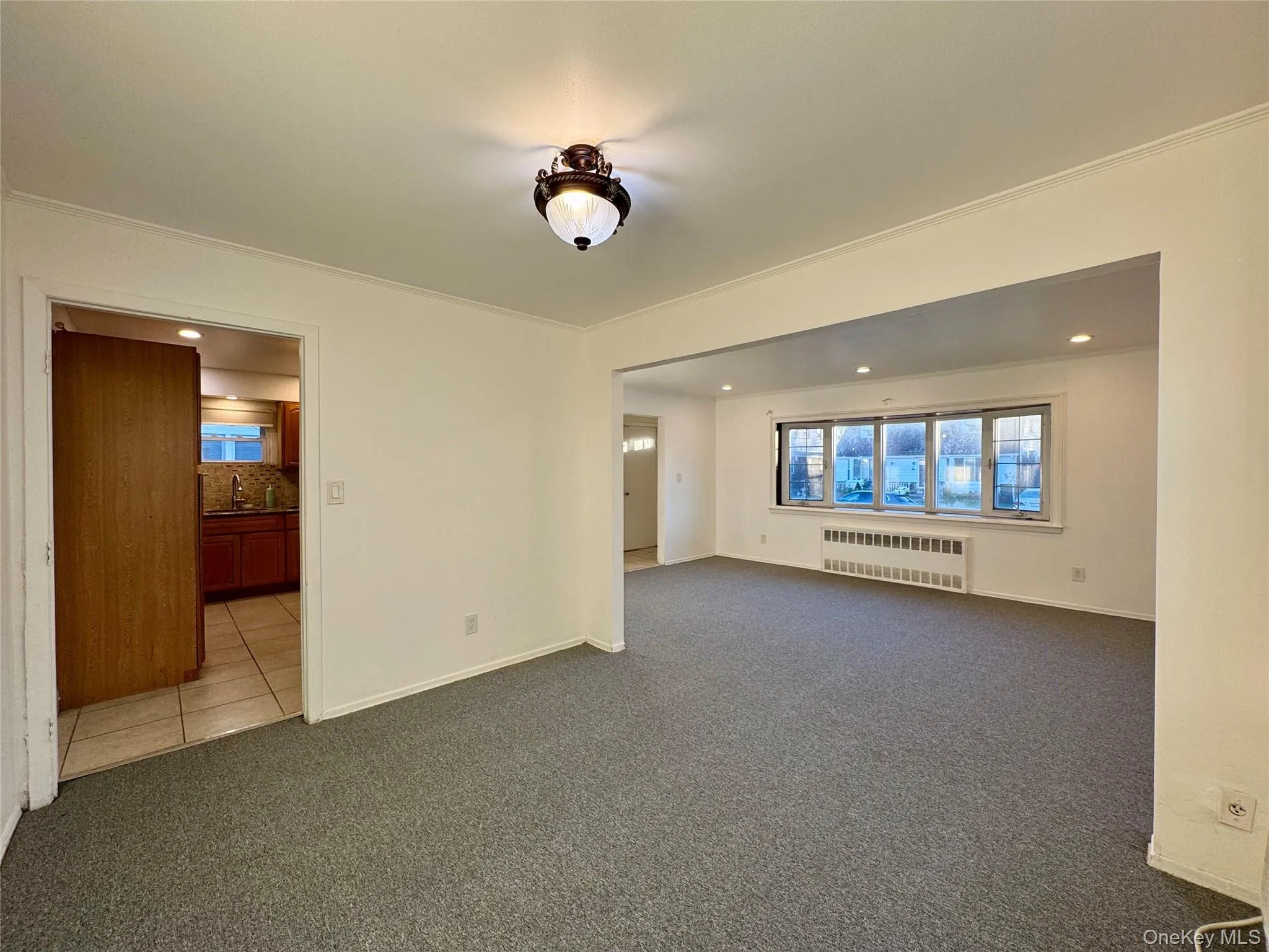 Empty room with carpet flooring, radiator heating unit, recessed lighting, and crown molding Empty room with carpet flooring, radiator heating unit, recessed lighting, and crown molding