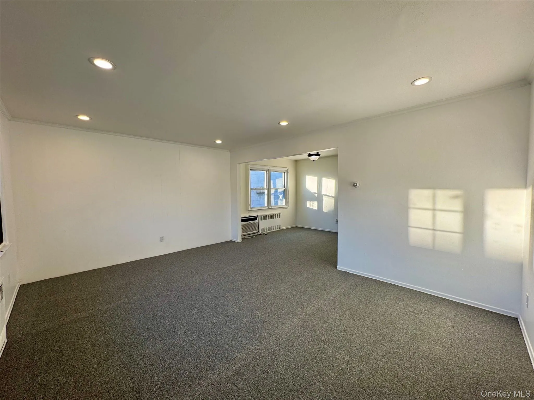 Spare room featuring recessed lighting, crown molding, carpet floors, and radiator heating unit Spare room featuring recessed lighting, crown molding, carpet floors, and radiator heating unit