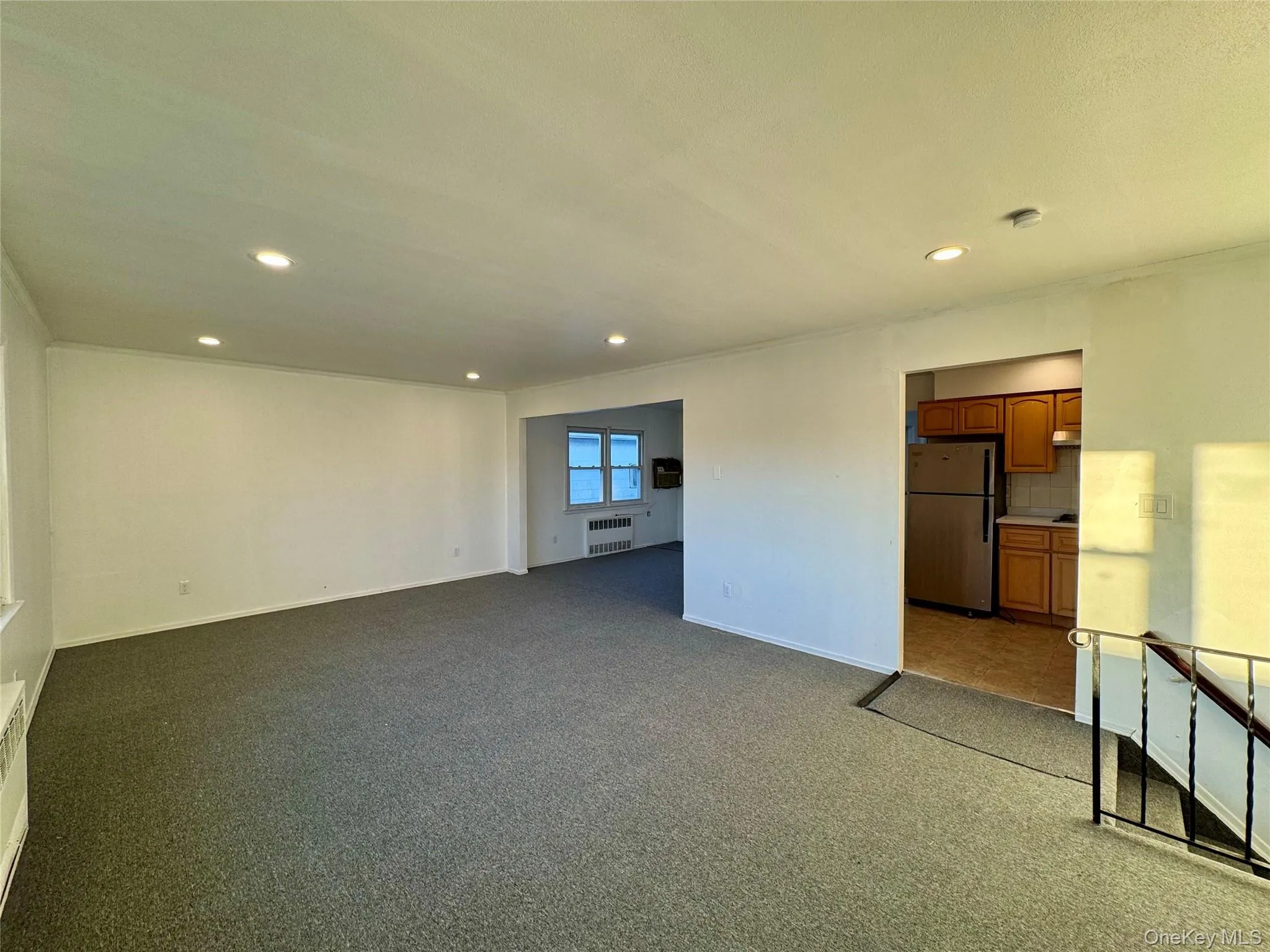 Unfurnished living room with recessed lighting, dark carpet, and radiator Unfurnished living room with recessed lighting, dark carpet, and radiator
