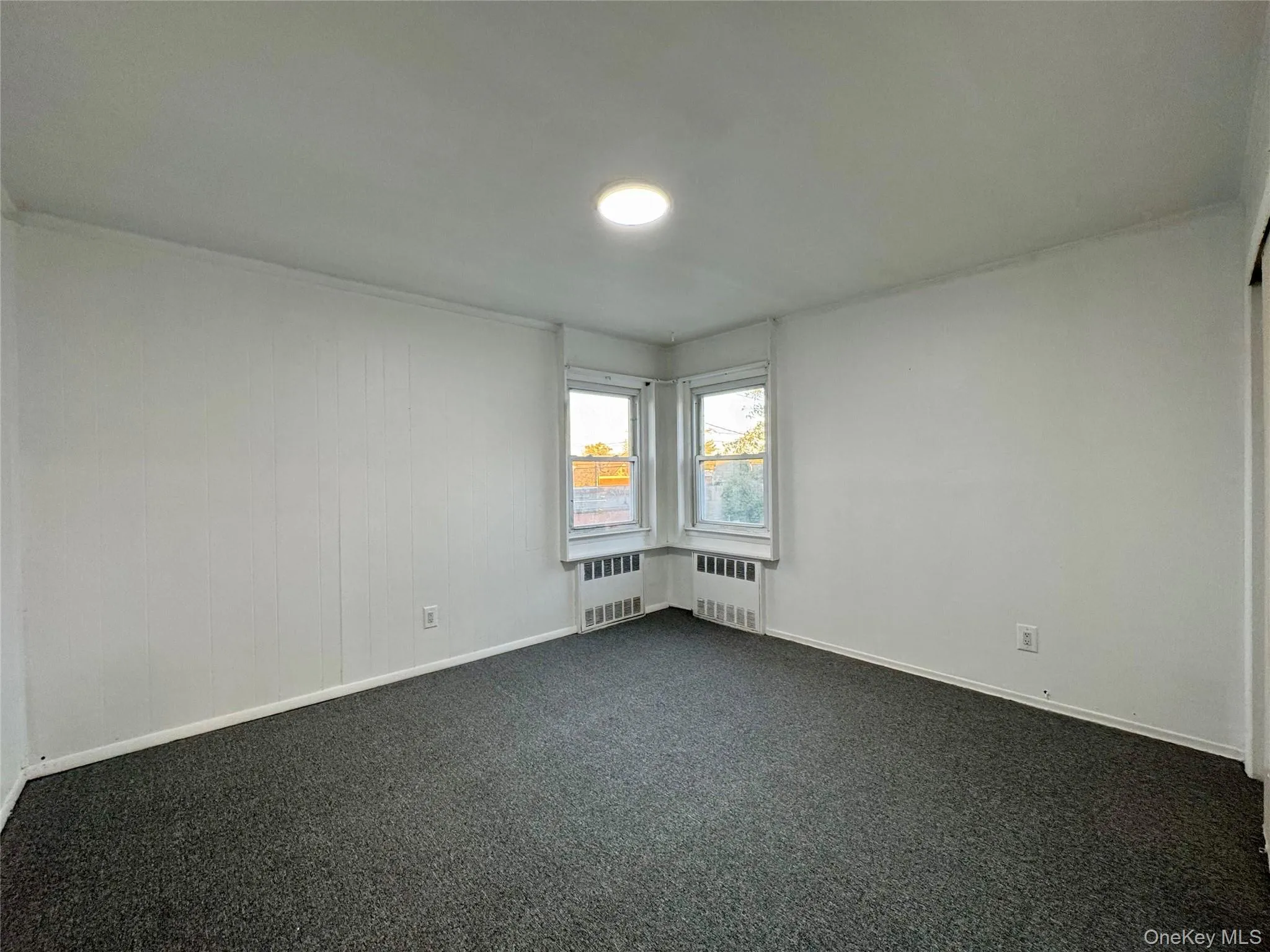 Empty room with dark carpet and radiator heating unit Empty room with dark carpet and radiator heating unit