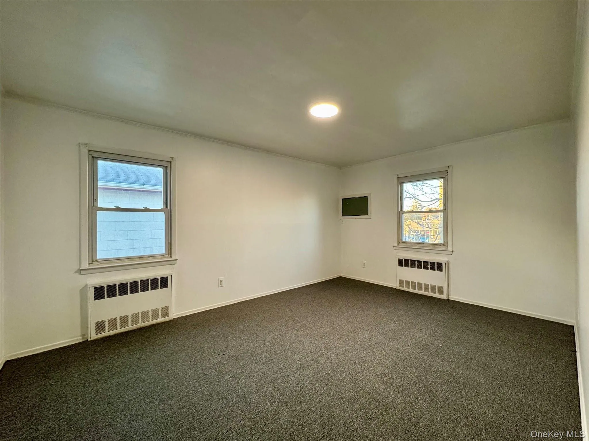 Empty room with radiator heating unit and carpet flooring Empty room with radiator heating unit and carpet flooring