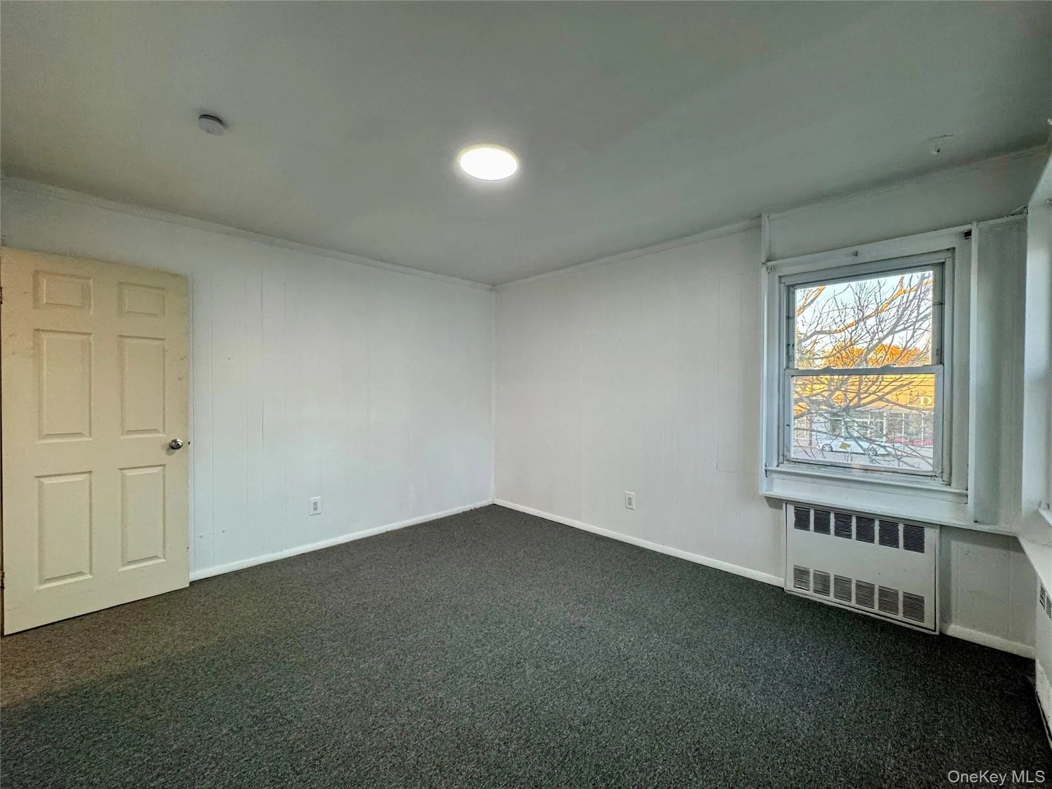 Unfurnished room with radiator, dark carpet, and crown molding Unfurnished room with radiator, dark carpet, and crown molding