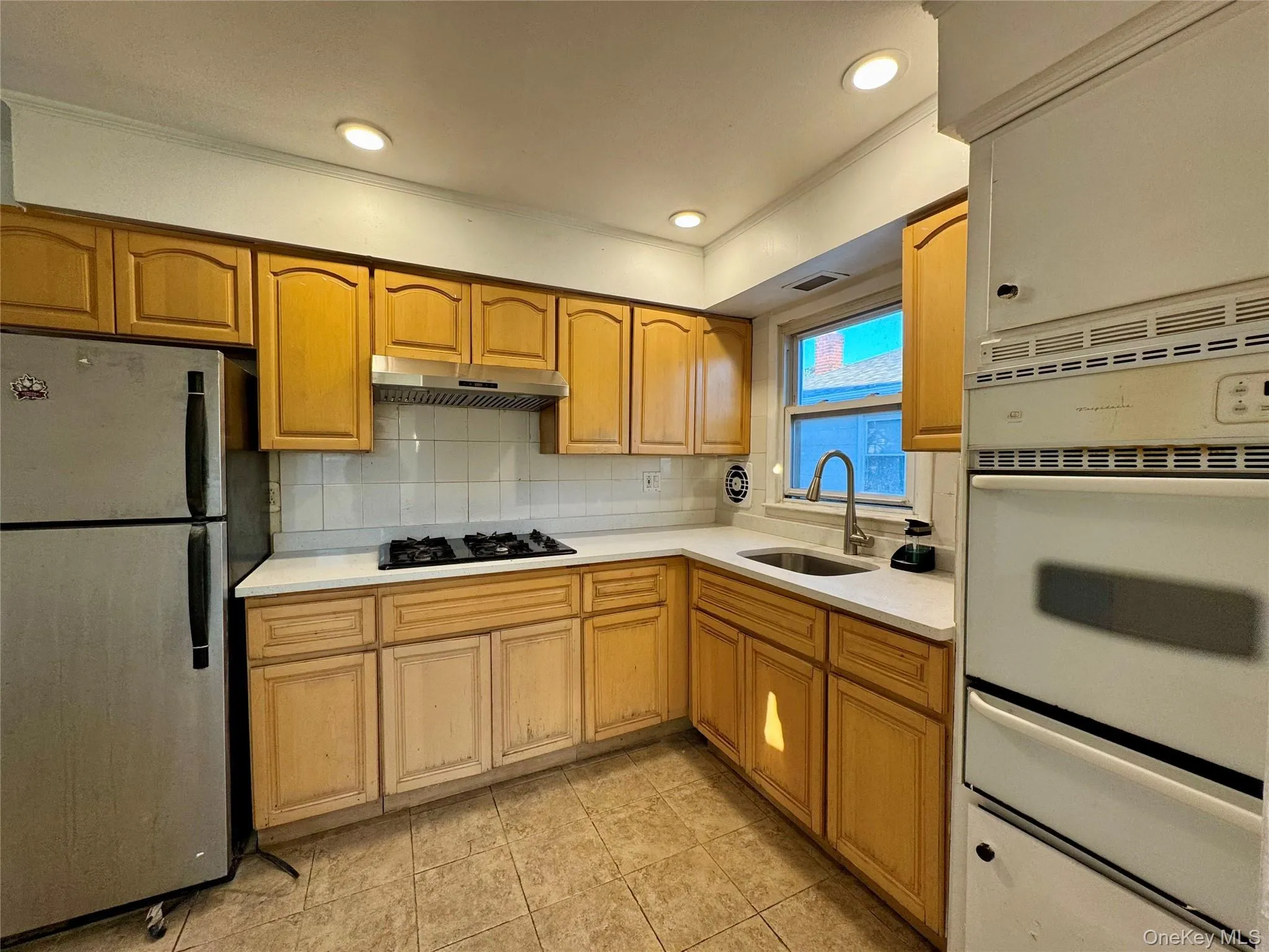 Kitchen featuring freestanding refrigerator, backsplash, a warming drawer, recessed lighting, and ornamental molding Kitchen featuring freestanding refrigerator, backsplash, a warming drawer, recessed lighting, and ornamental molding