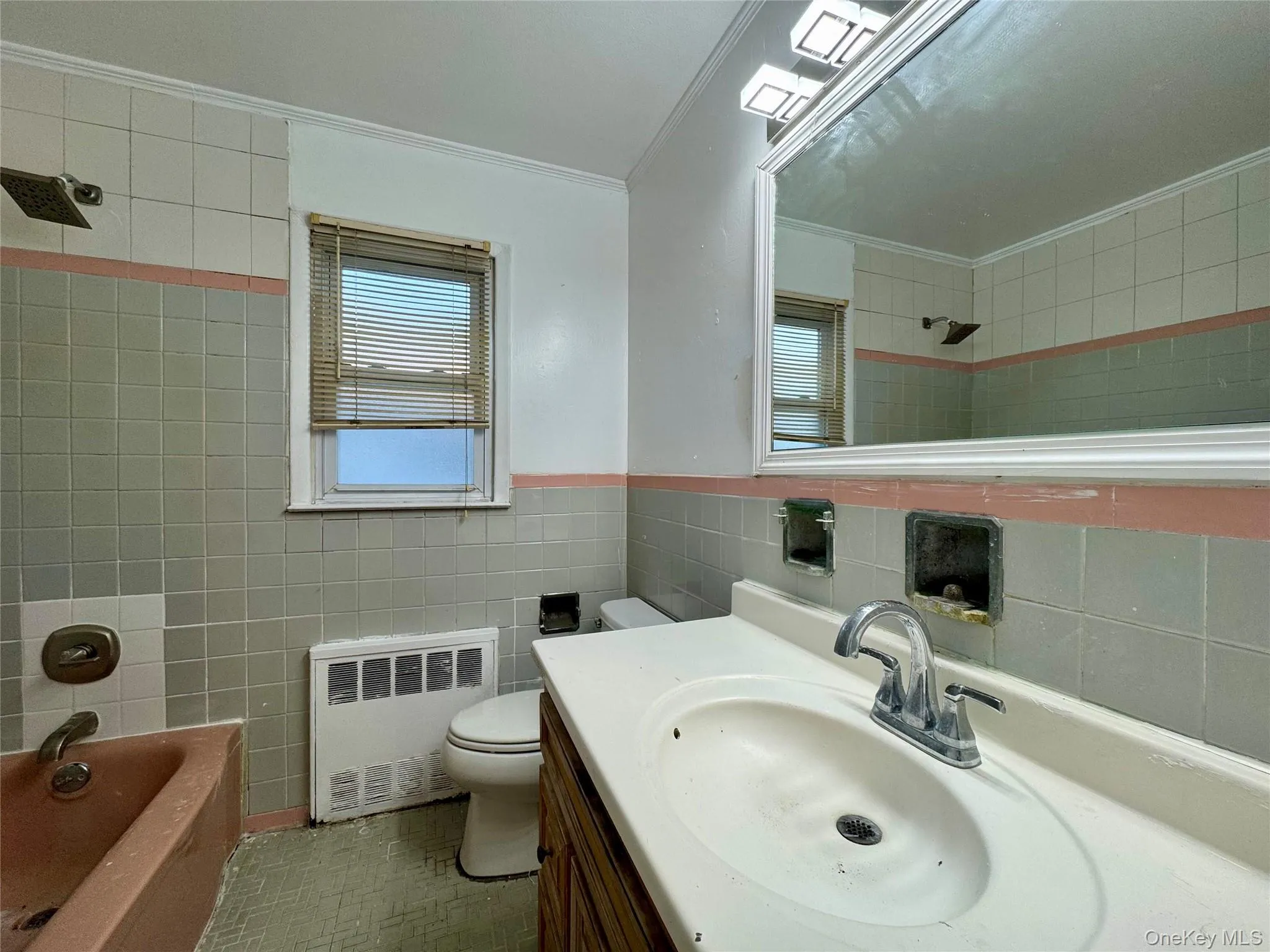 Full bath with radiator heating unit, vanity, tile walls, ornamental molding, and tub / shower combination Full bath with radiator heating unit, vanity, tile walls, ornamental molding, and tub / shower combination