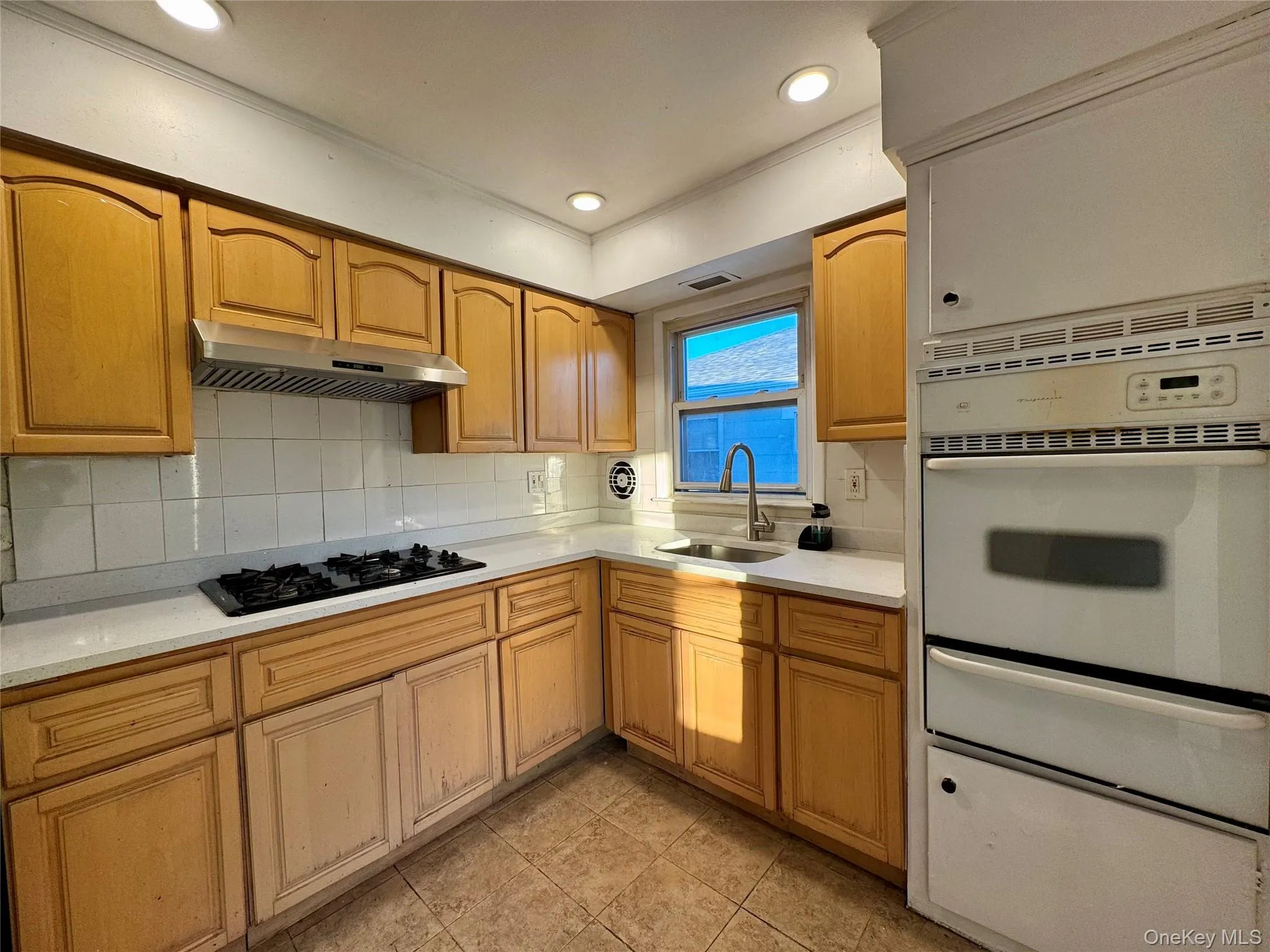 Kitchen featuring decorative backsplash, a warming drawer, oven, recessed lighting, and light stone counters Kitchen featuring decorative backsplash, a warming drawer, oven, recessed lighting, and light stone counters