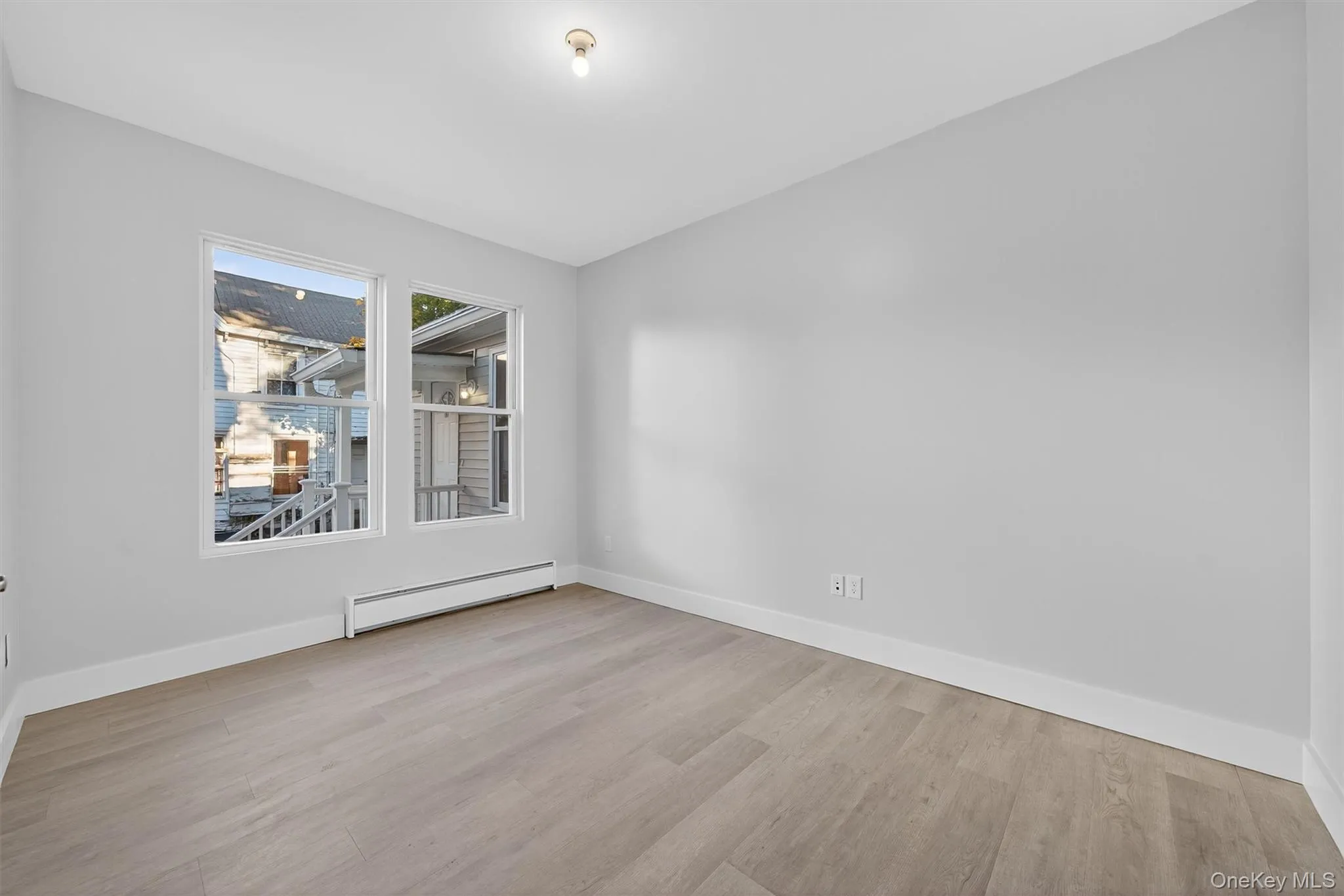 Unfurnished room featuring baseboard heating and light wood-style flooring Unfurnished room featuring baseboard heating and light wood-style flooring