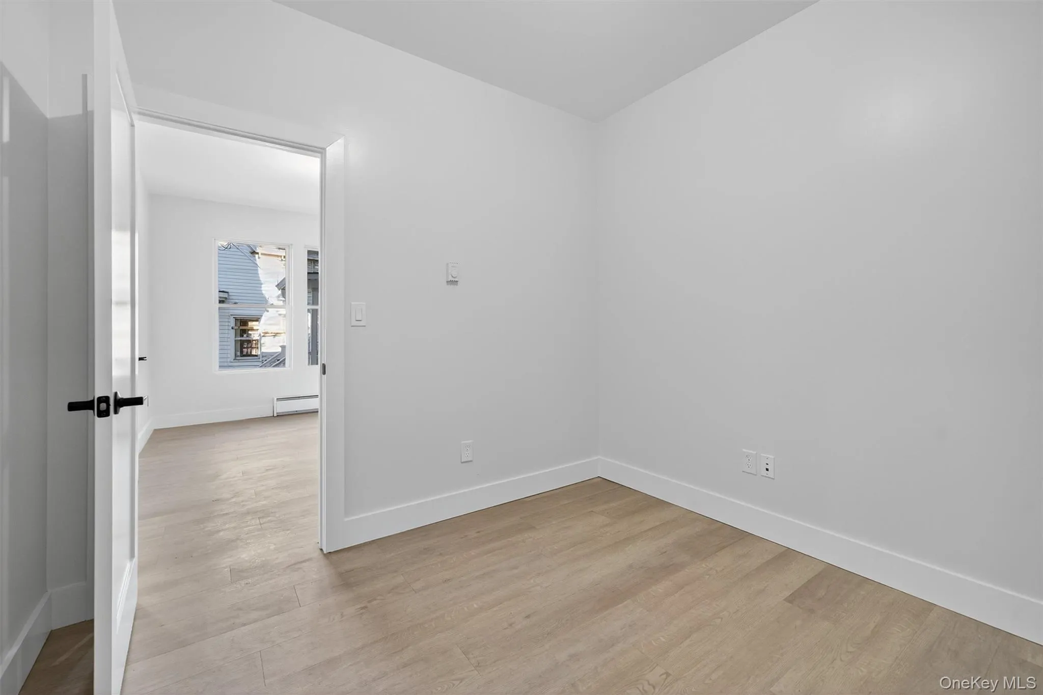 Empty room with light wood finished floors and a baseboard radiator Empty room with light wood finished floors and a baseboard radiator