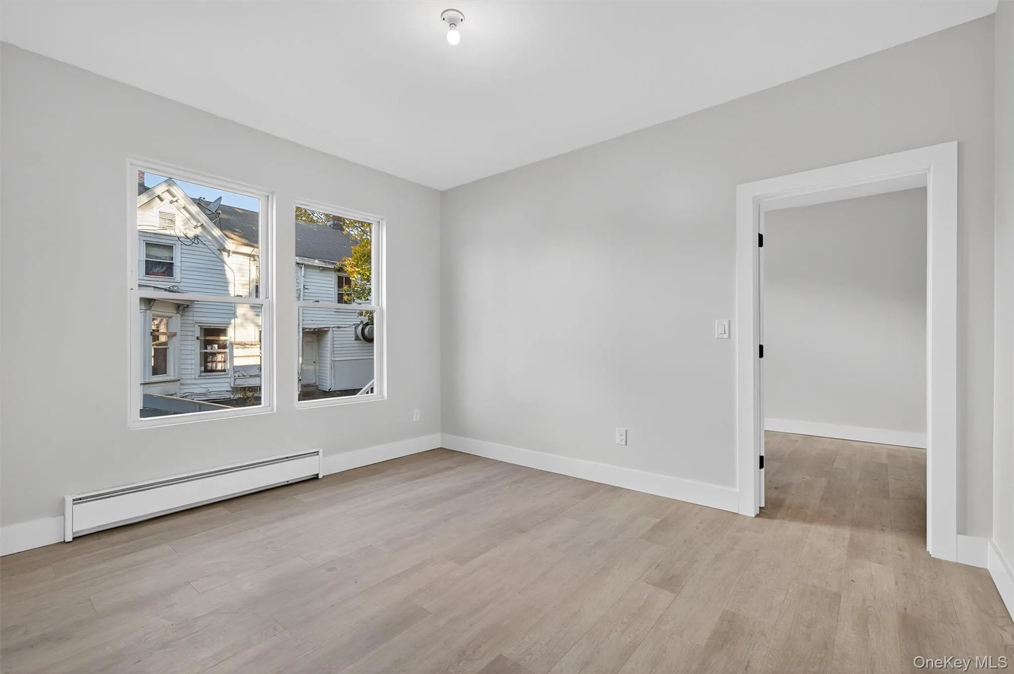 Empty room with baseboard heating and light wood-style floors Empty room with baseboard heating and light wood-style floors