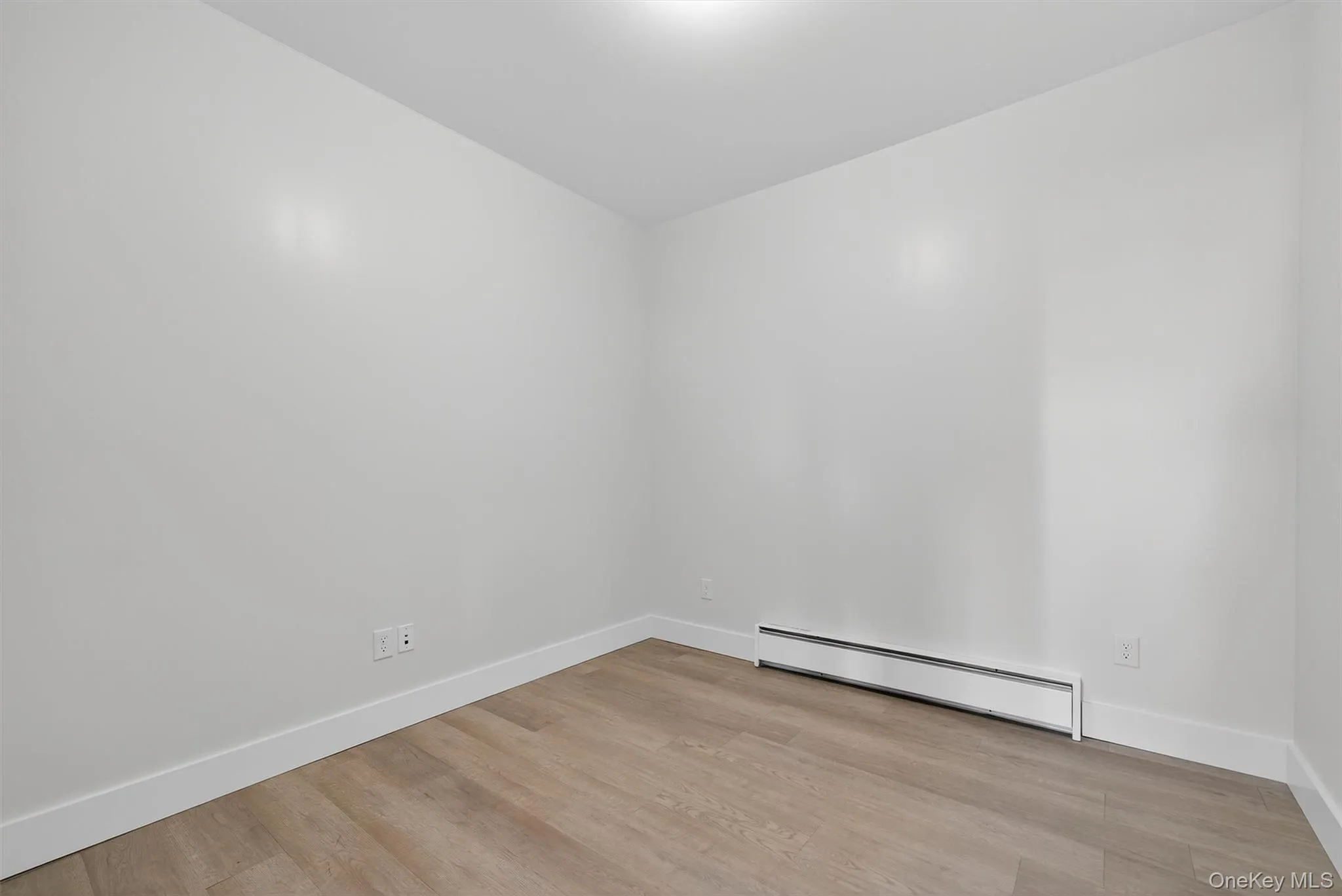 Spare room featuring a baseboard heating unit and light wood-type flooring Spare room featuring a baseboard heating unit and light wood-type flooring