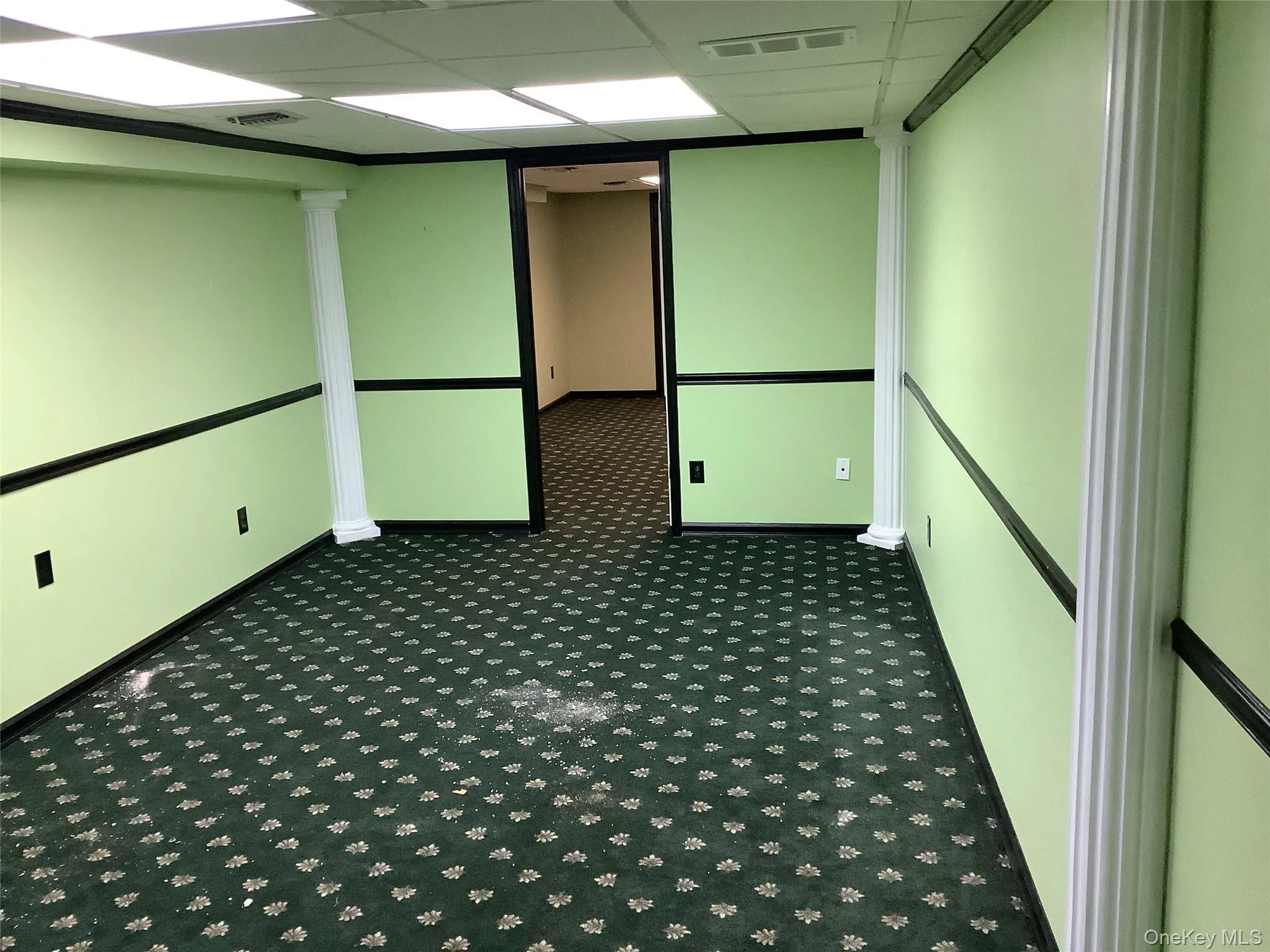 Carpeted empty room with a drop ceiling and baseboards Carpeted empty room with a drop ceiling and baseboards