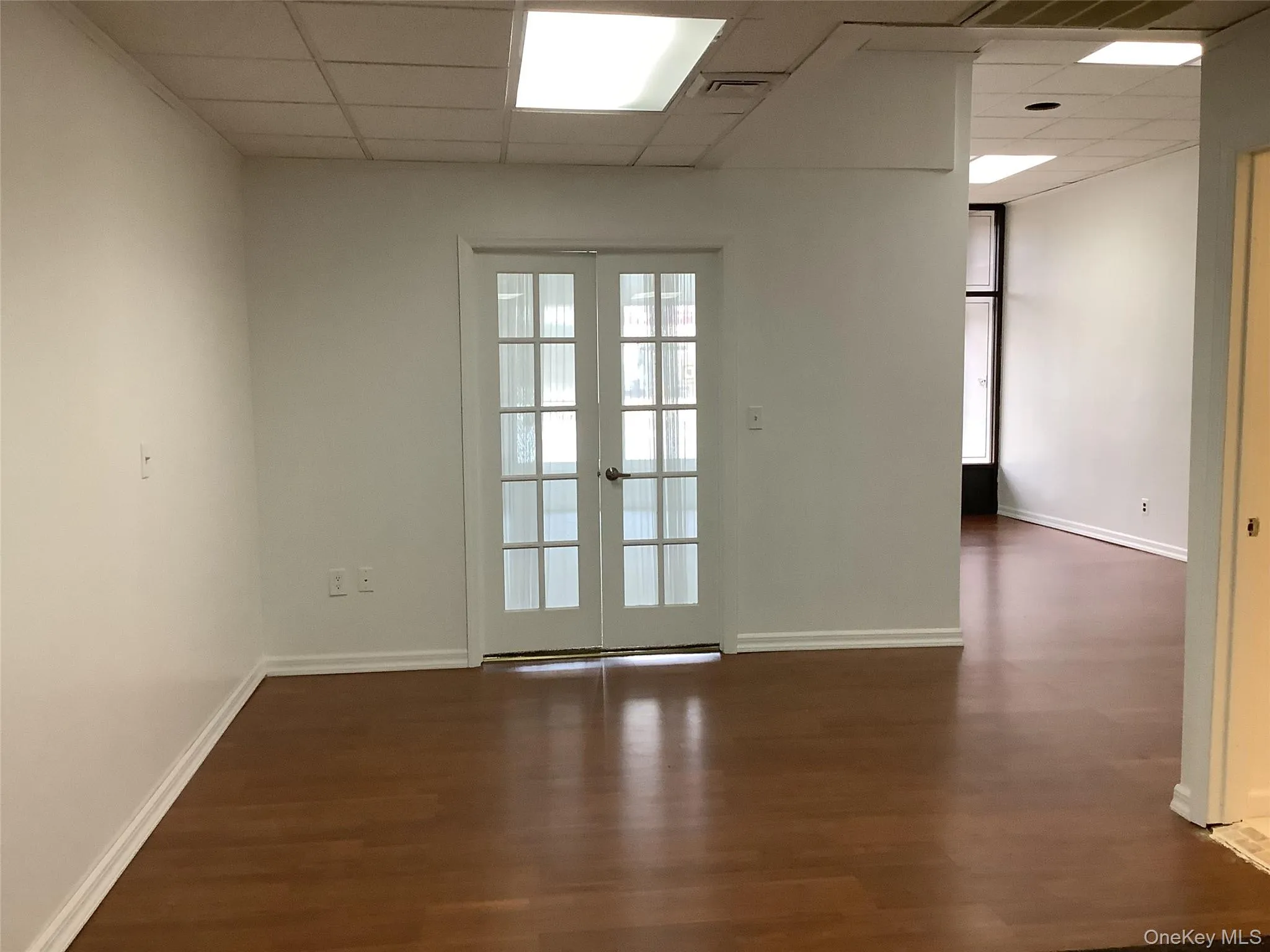 Unfurnished room with a paneled ceiling, french doors, and dark wood finished floors Unfurnished room with a paneled ceiling, french doors, and dark wood finished floors