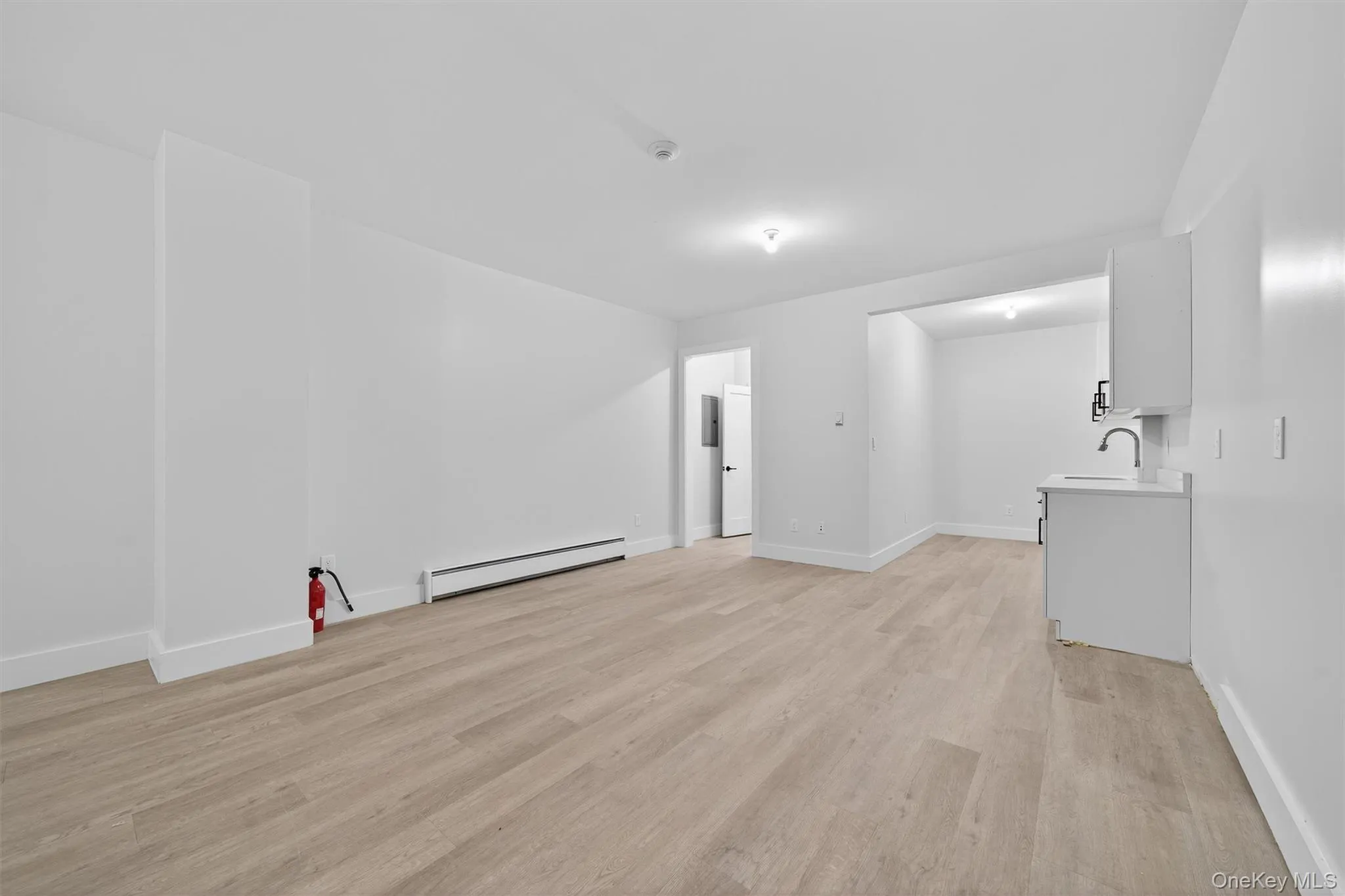 Unfurnished living room with light wood-style flooring and a baseboard heating unit Unfurnished living room with light wood-style flooring and a baseboard heating unit