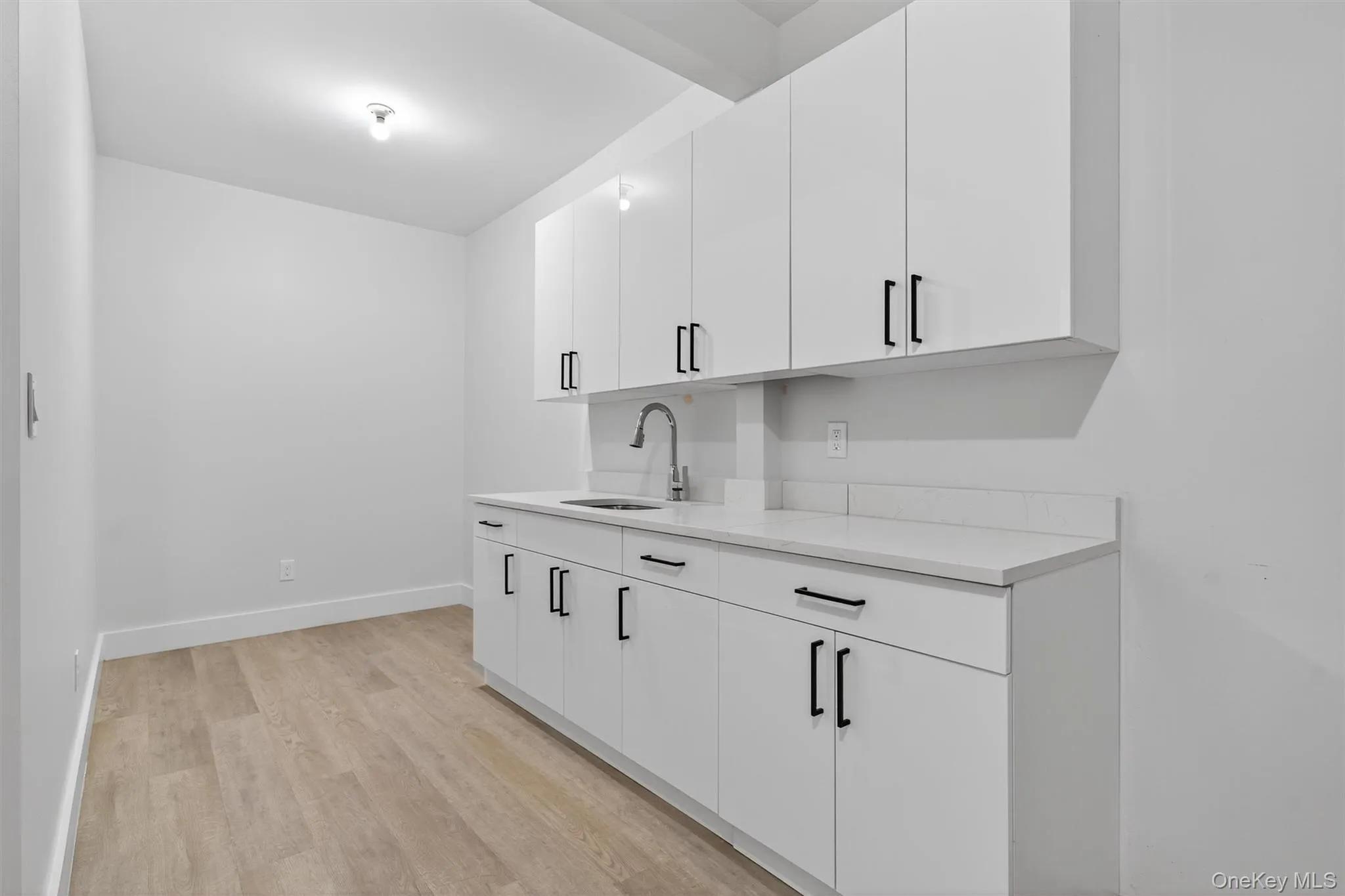 Bar with white cabinetry, light wood-type flooring, light stone countertops, and modern cabinets Bar with white cabinetry, light wood-type flooring, light stone countertops, and modern cabinets