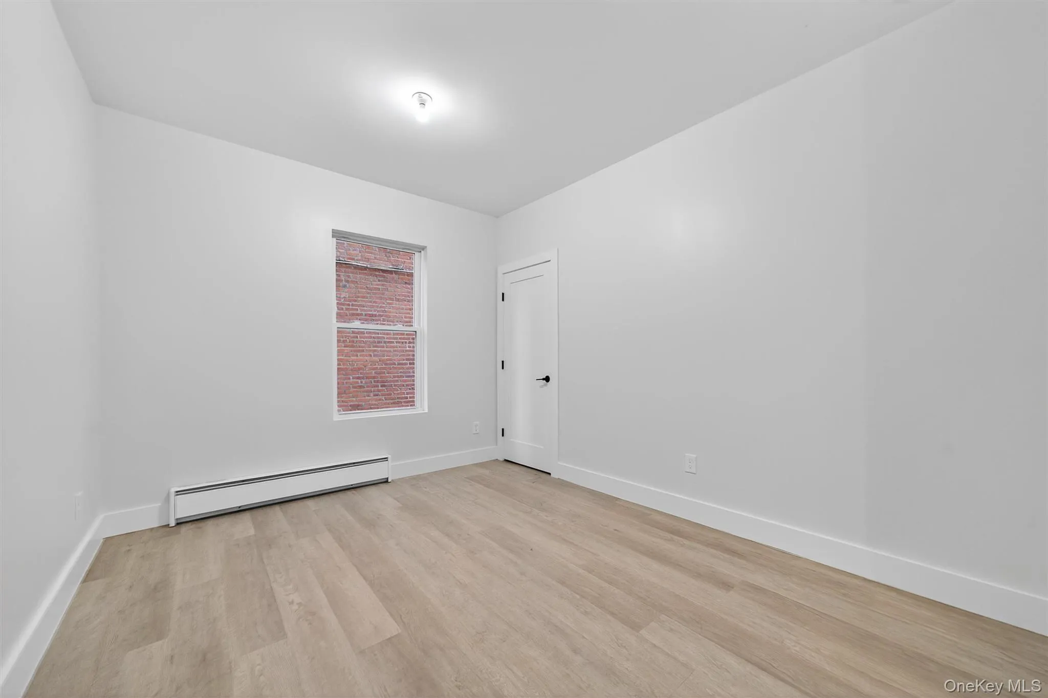 Empty room with a baseboard heating unit and light wood finished floors Empty room with a baseboard heating unit and light wood finished floors