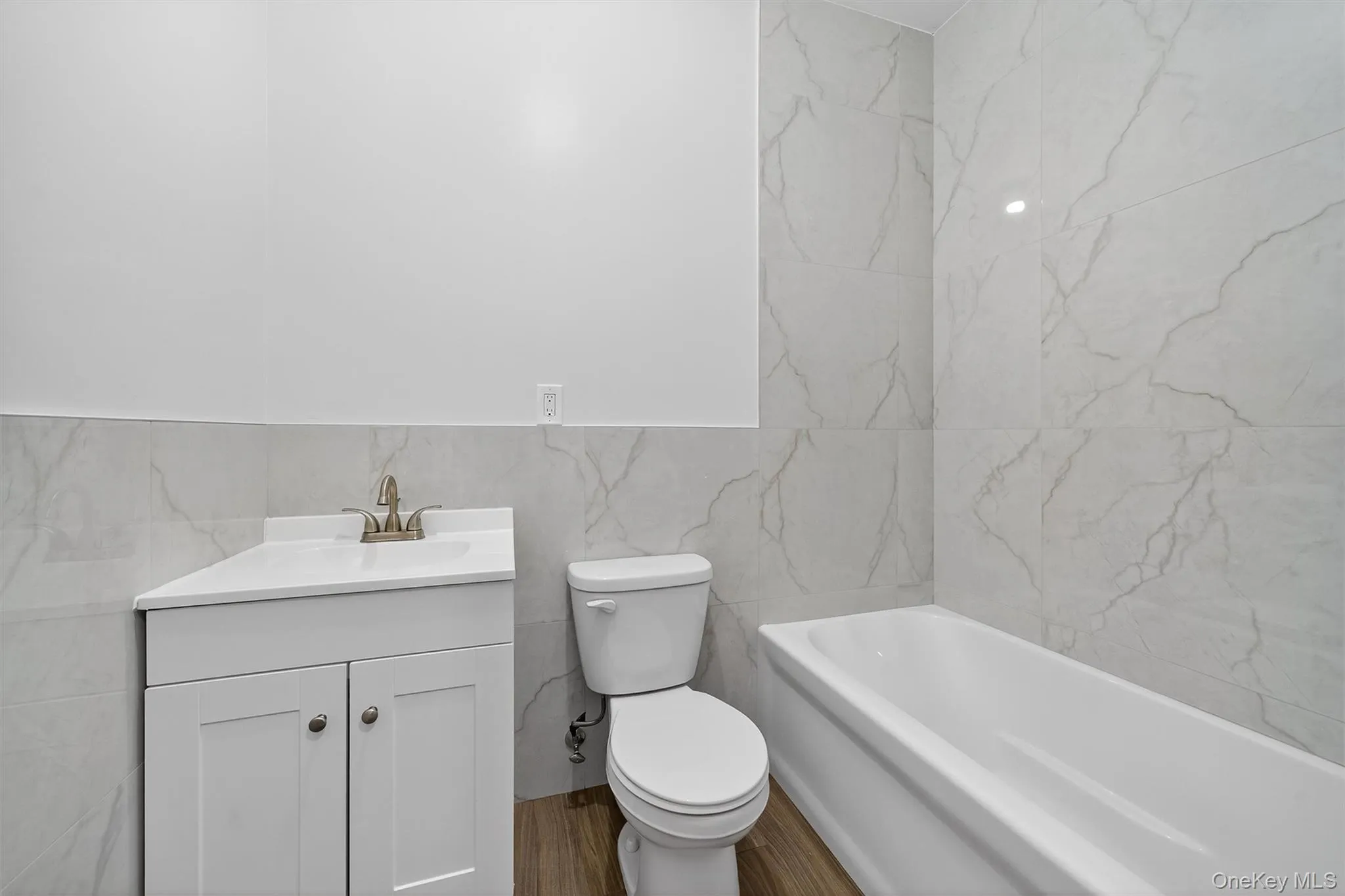 Bathroom with tile walls, vanity, a bath, and wood finished floors Bathroom with tile walls, vanity, a bath, and wood finished floors