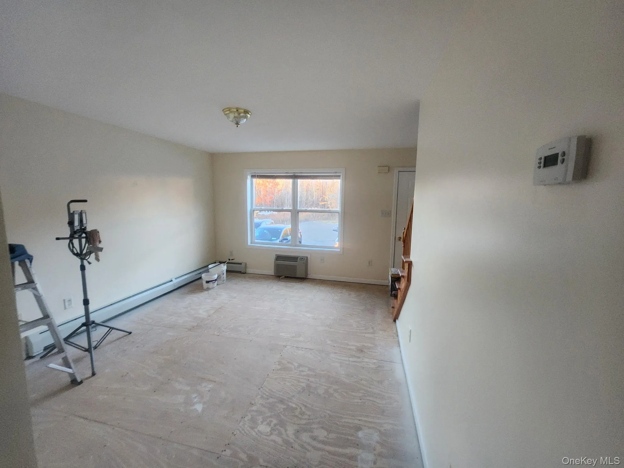 Unfurnished living room with a baseboard radiator and view of parking area. Unfurnished living room with a baseboard radiator and view of parking area.