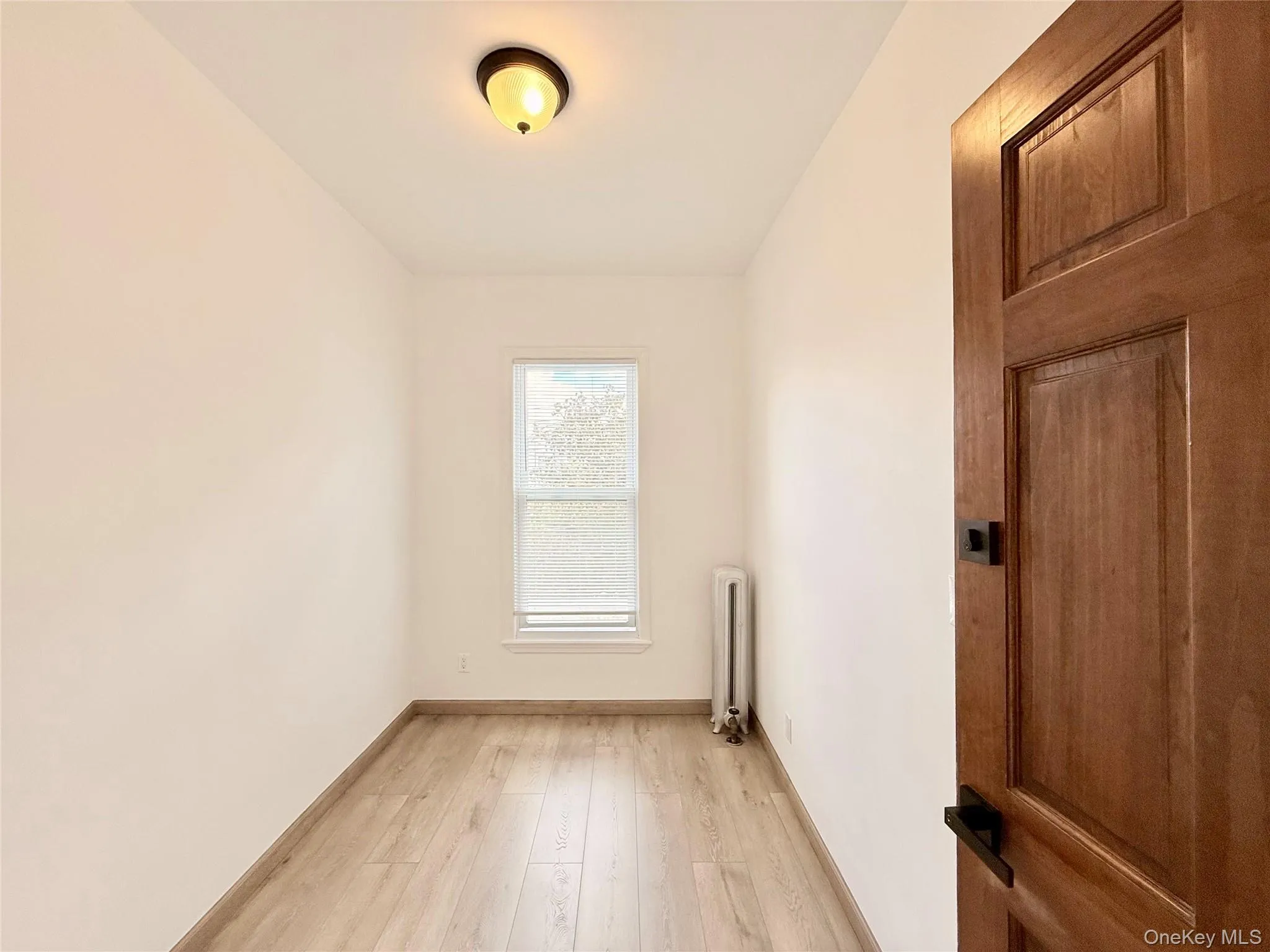 Empty room featuring light wood-style floors and radiator Empty room featuring light wood-style floors and radiator