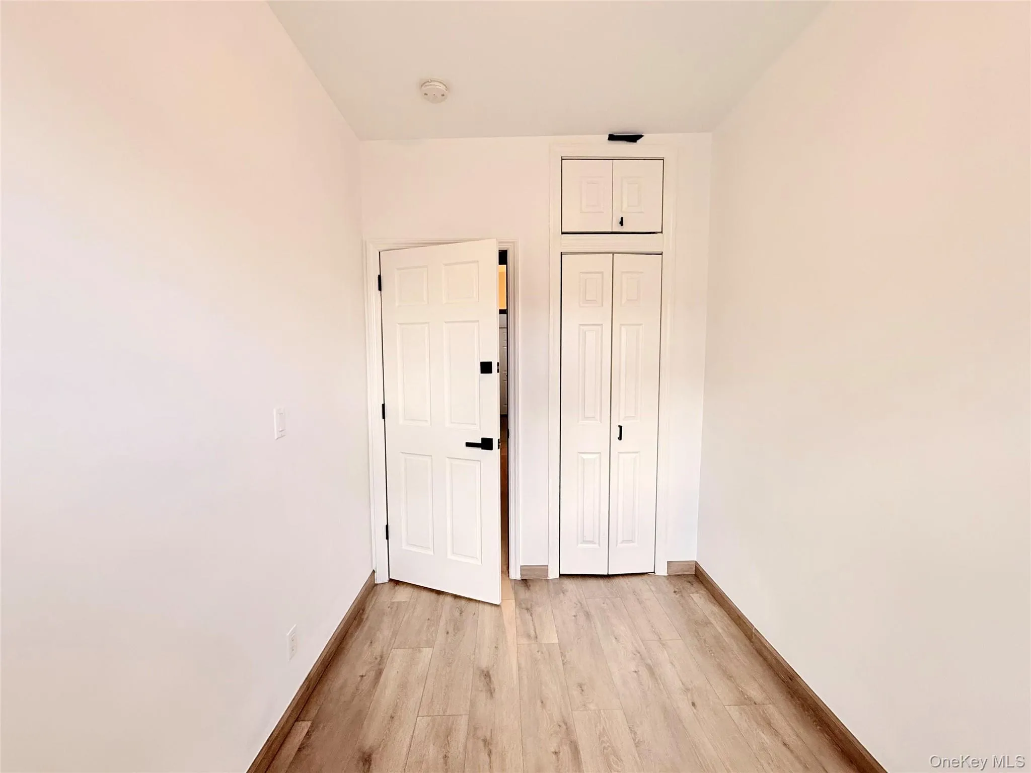 Spare room featuring light wood-style floors and baseboards Spare room featuring light wood-style floors and baseboards