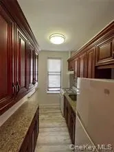 Kitchen featuring freestanding refrigerator, stainless steel gas range, light stone countertops, and light ceramic-style floor Kitchen featuring freestanding refrigerator, stainless steel gas range, light stone countertops, and light ceramic-style floor