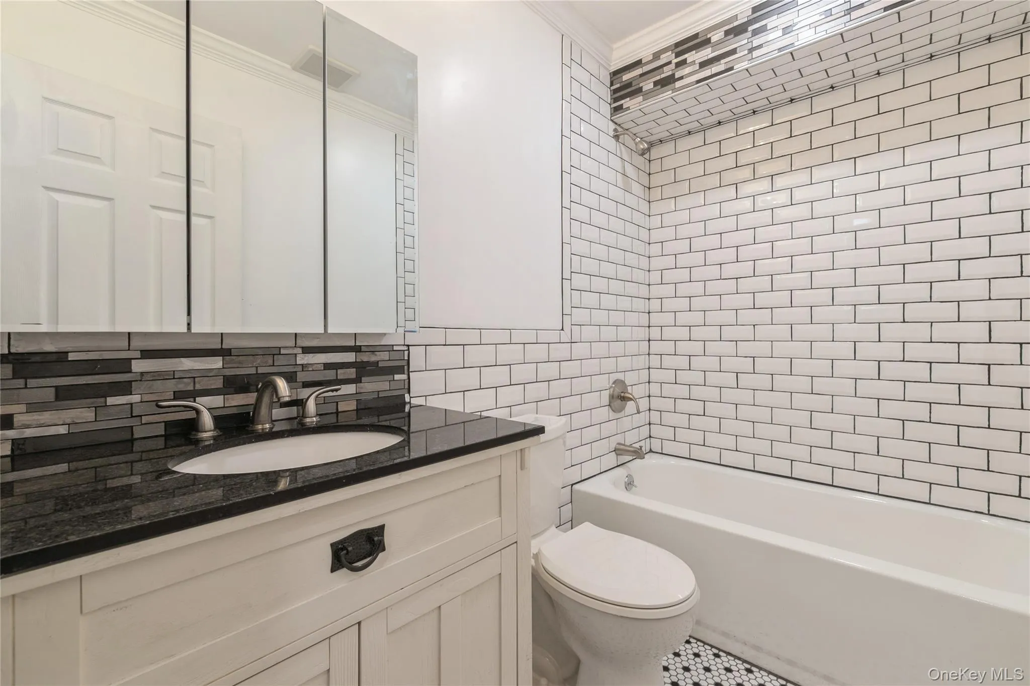Bathroom featuring vanity, tile walls, washtub / shower combination, ornamental molding, and tasteful backsplash Bathroom featuring vanity, tile walls, washtub / shower combination, ornamental molding, and tasteful backsplash