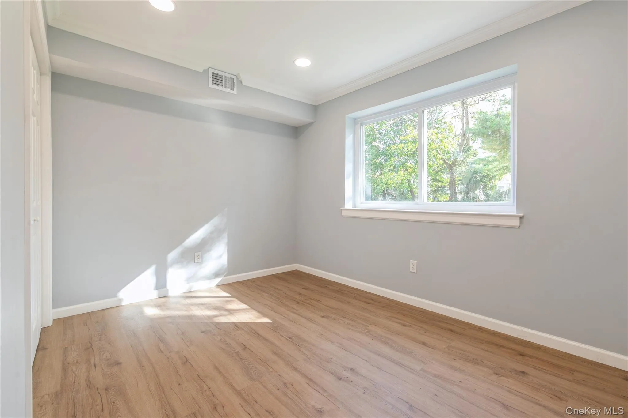 Empty room with ornamental molding, light wood-type flooring, and recessed lighting Empty room with ornamental molding, light wood-type flooring, and recessed lighting