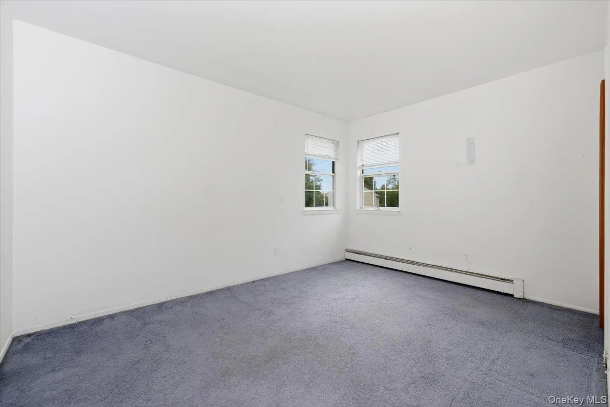 Empty room featuring a baseboard heating unit and carpet Empty room featuring a baseboard heating unit and carpet