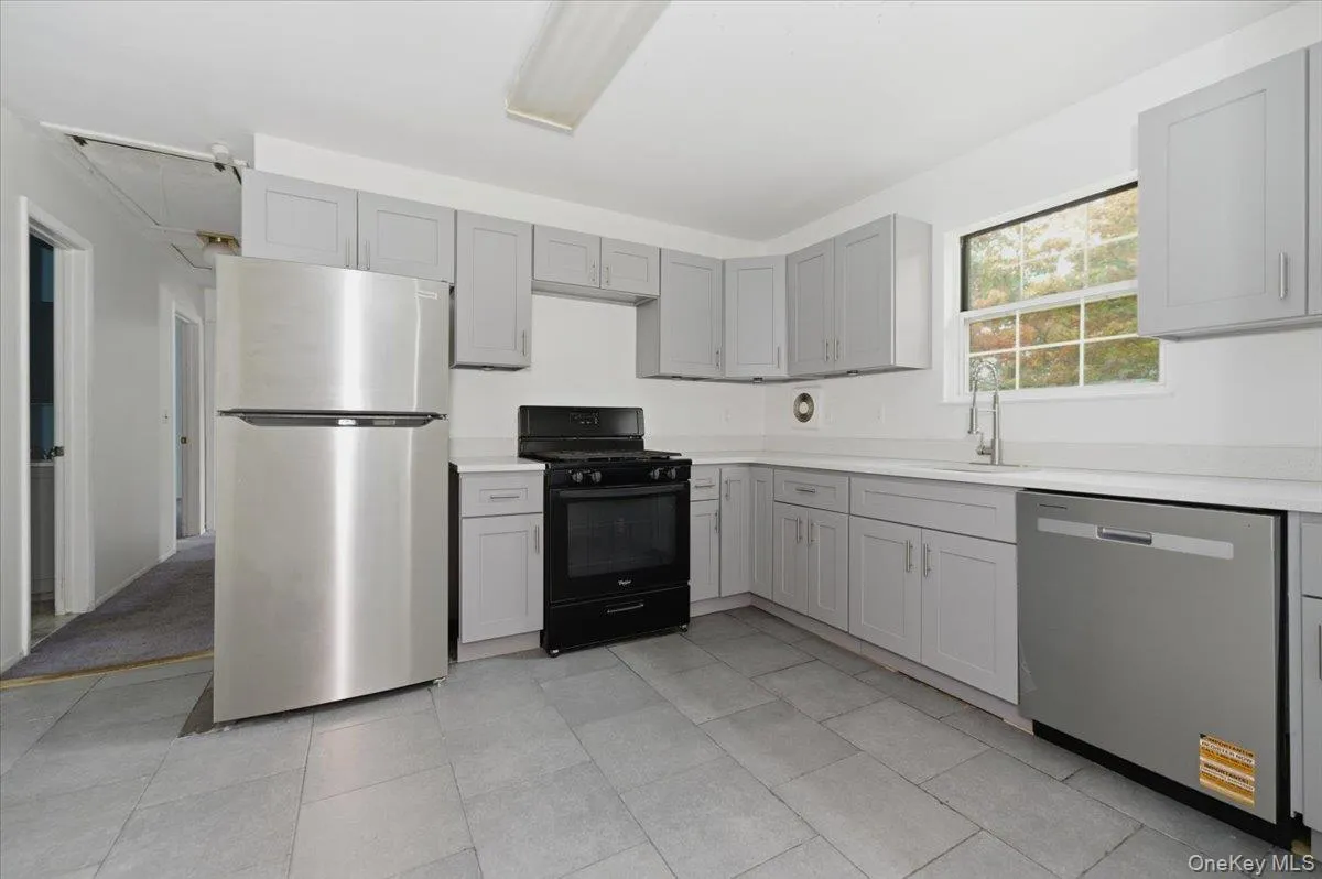 Kitchen with appliances with stainless steel finishes, gray cabinetry, and light tile patterned flooring Kitchen with appliances with stainless steel finishes, gray cabinetry, and light tile patterned flooring