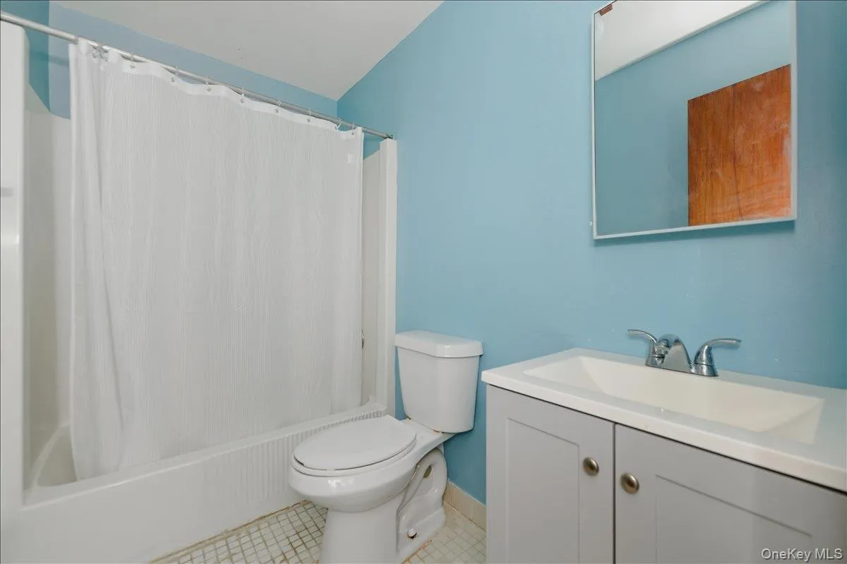 Bathroom with vanity, shower / tub combo with curtain, and light tile patterned flooring Bathroom with vanity, shower / tub combo with curtain, and light tile patterned flooring