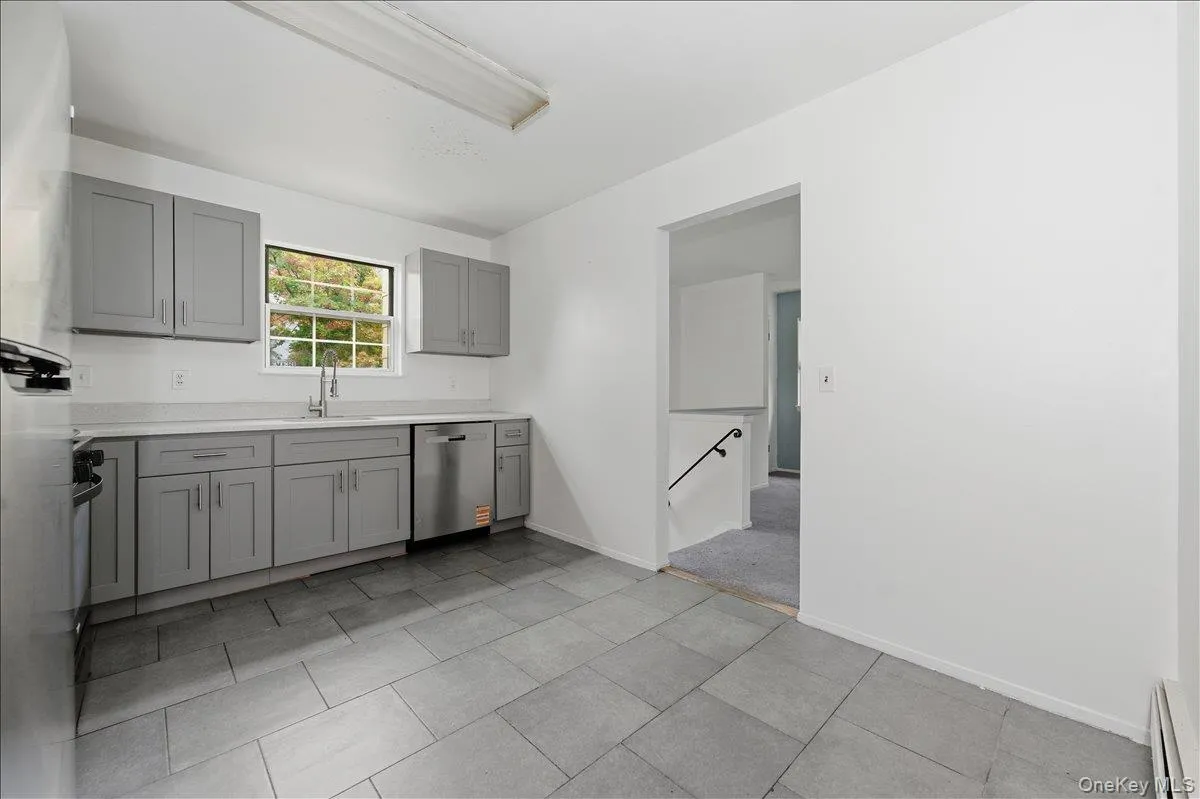 Kitchen with gray cabinets, stainless steel appliances, a baseboard radiator, and light tile patterned floors Kitchen with gray cabinets, stainless steel appliances, a baseboard radiator, and light tile patterned floors