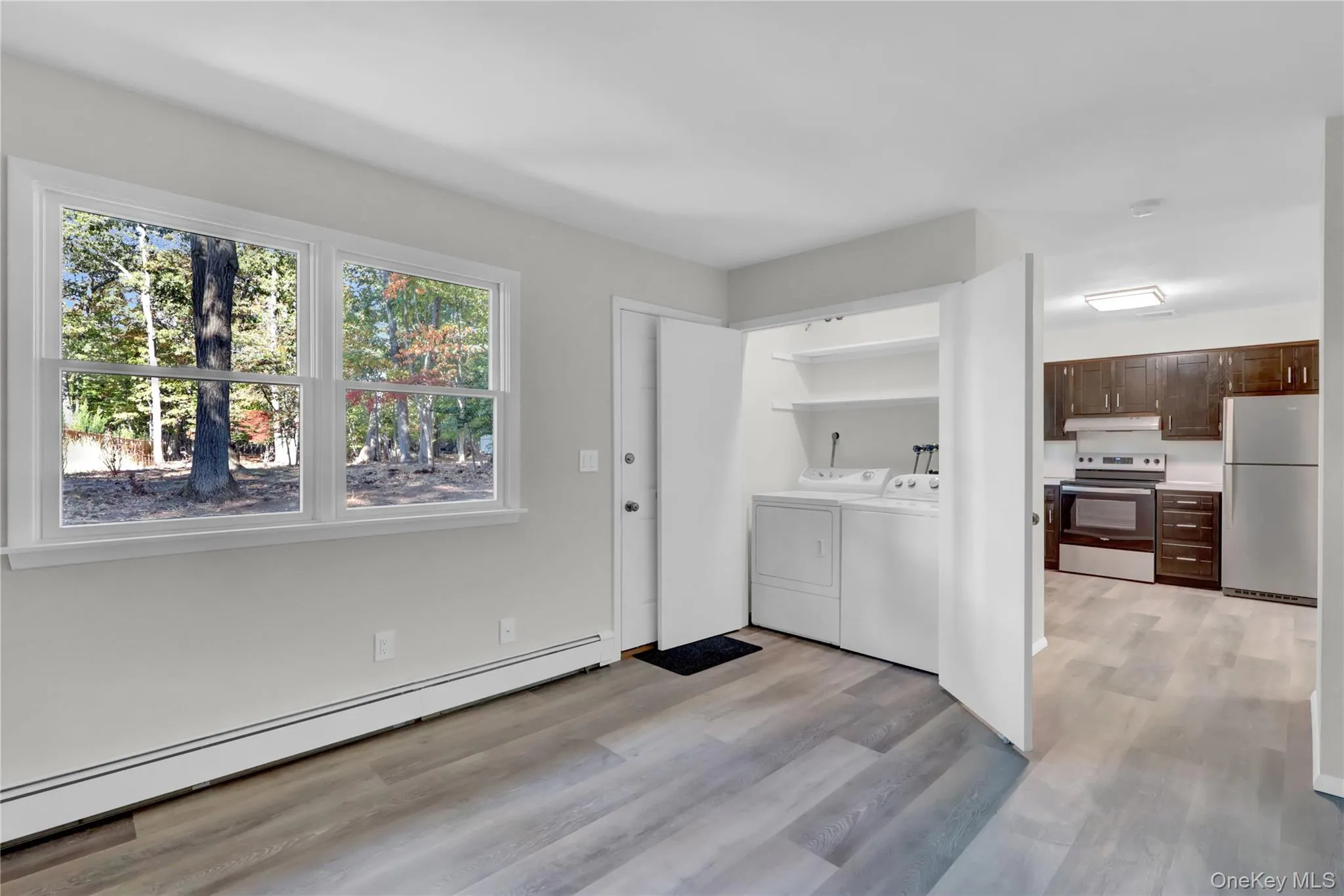 Laundry room featuring a baseboard heating unit, independent washer and dryer, and light wood-type flooring Laundry room featuring a baseboard heating unit, independent washer and dryer, and light wood-type flooring