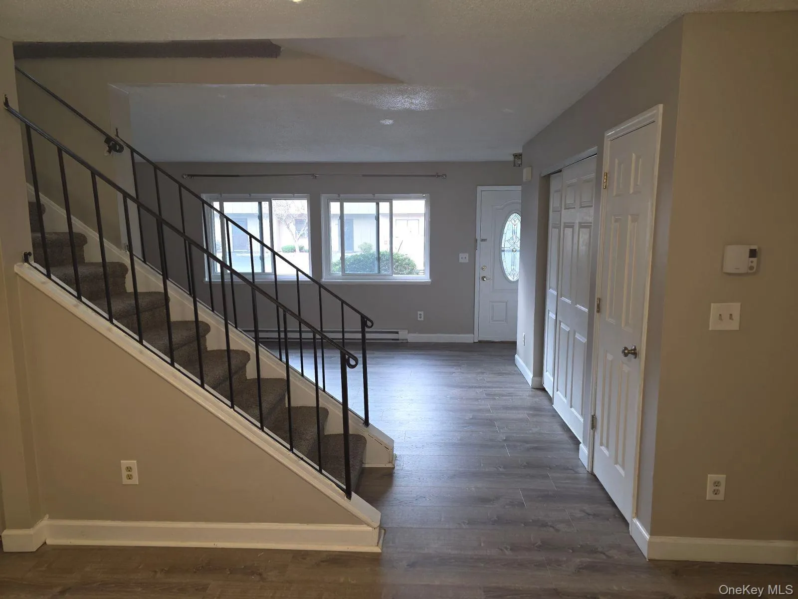 Foyer with stairway, dark wood-style floors, and a baseboard heating unit Foyer with stairway, dark wood-style floors, and a baseboard heating unit