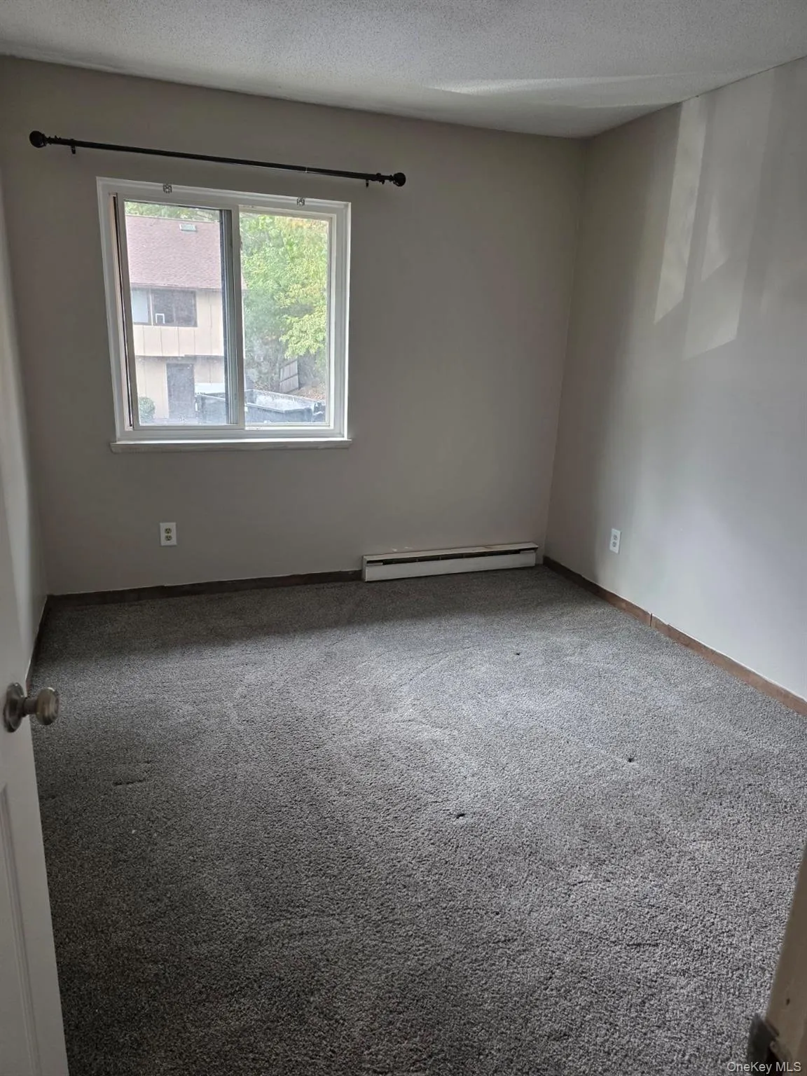 Spare room with carpet, a baseboard heating unit, and a textured ceiling Spare room with carpet, a baseboard heating unit, and a textured ceiling