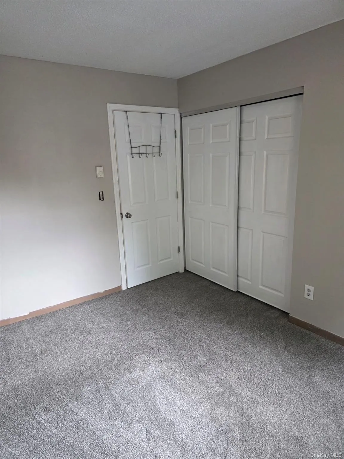 Unfurnished bedroom featuring a closet, carpet flooring, and a textured ceiling Unfurnished bedroom featuring a closet, carpet flooring, and a textured ceiling