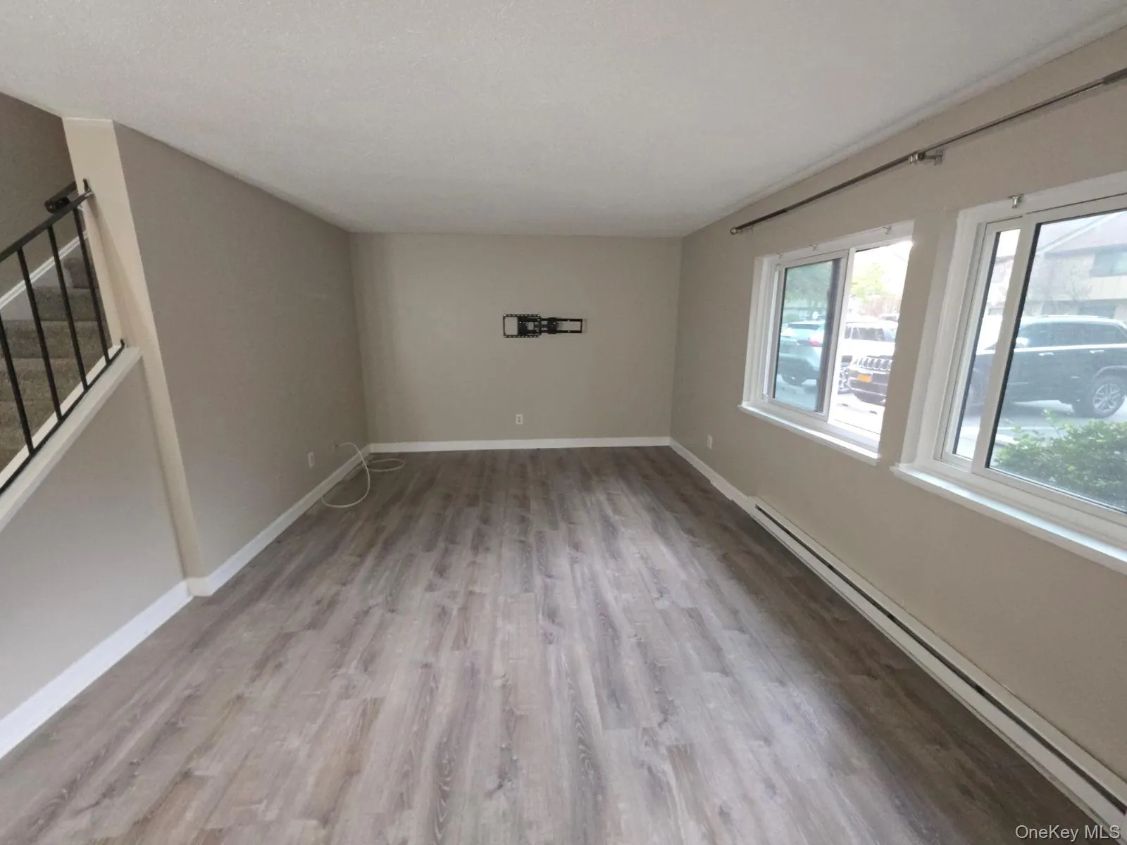 Spare room with baseboard heating, stairs, and light wood-style flooring Spare room with baseboard heating, stairs, and light wood-style flooring