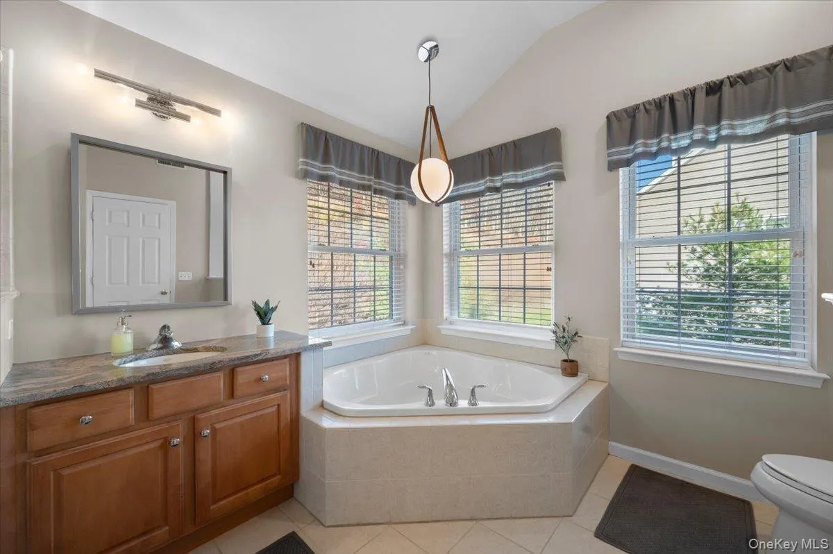 Full bathroom featuring a bath, light tile patterned flooring, lofted ceiling, and vanity Full bathroom featuring a bath, light tile patterned flooring, lofted ceiling, and vanity