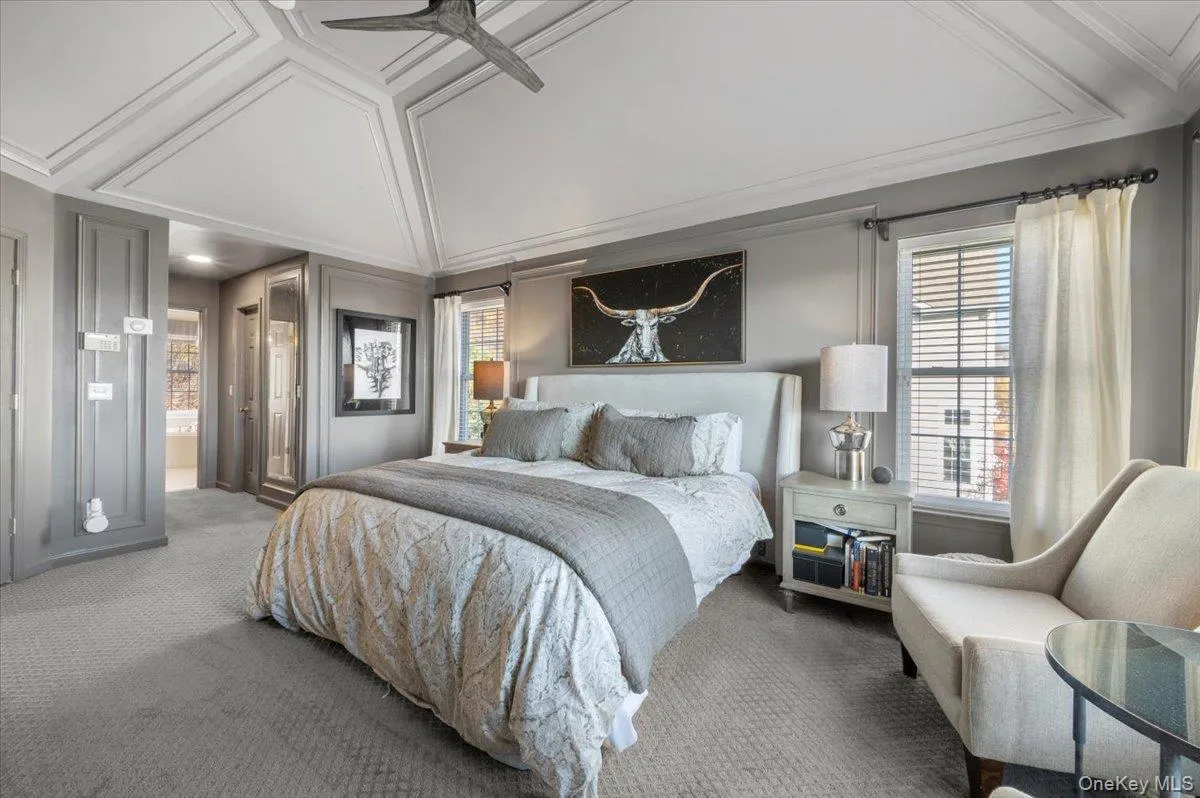 Bedroom with connected bathroom, carpet flooring, a ceiling fan, and ornamental molding Bedroom with connected bathroom, carpet flooring, a ceiling fan, and ornamental molding