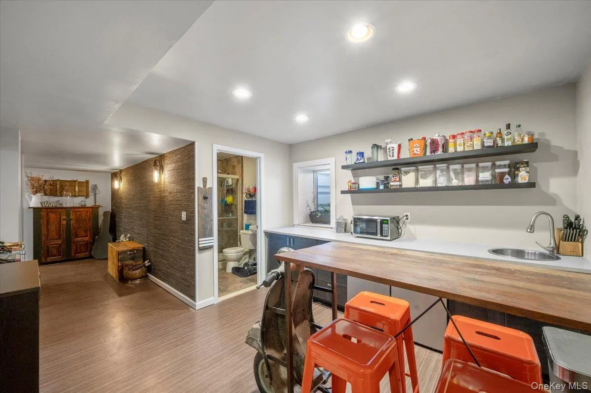 Bar with light wood finished floors, butcher block counters, recessed lighting, open shelves, and brick wall Bar with light wood finished floors, butcher block counters, recessed lighting, open shelves, and brick wall