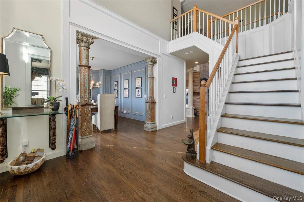Entryway with dark wood finished floors, a decorative wall, ornate columns, and stairway Entryway with dark wood finished floors, a decorative wall, ornate columns, and stairway