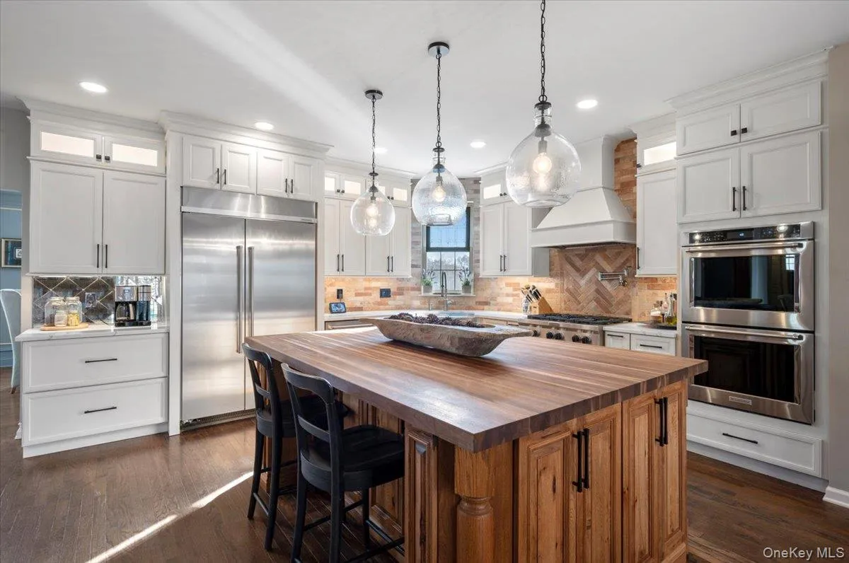 Kitchen with glass insert cabinets, wooden counters, stainless steel appliances, white cabinets, and recessed lighting Kitchen with glass insert cabinets, wooden counters, stainless steel appliances, white cabinets, and recessed lighting