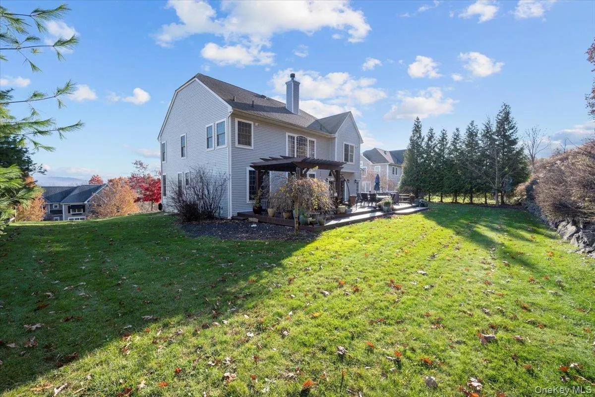 Rear view of property with a chimney, a deck, and a yard Rear view of property with a chimney, a deck, and a yard