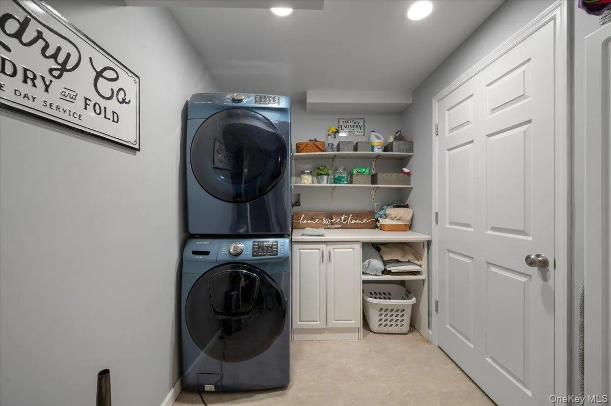 Washroom with stacked washer and clothes dryer, recessed lighting, and cabinet space Washroom with stacked washer and clothes dryer, recessed lighting, and cabinet space