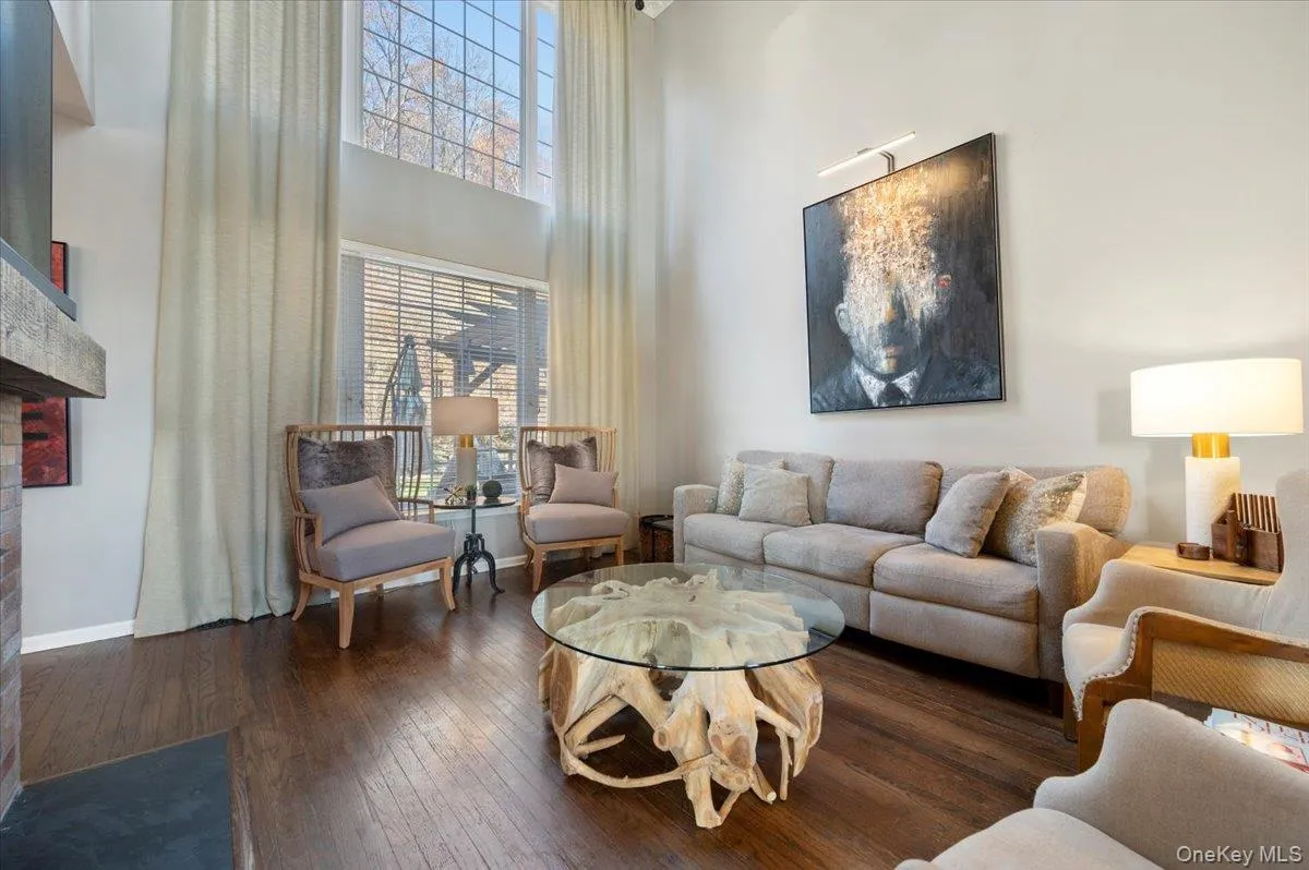 Living area with a towering ceiling, hardwood / wood-style flooring, and a brick fireplace Living area with a towering ceiling, hardwood / wood-style flooring, and a brick fireplace