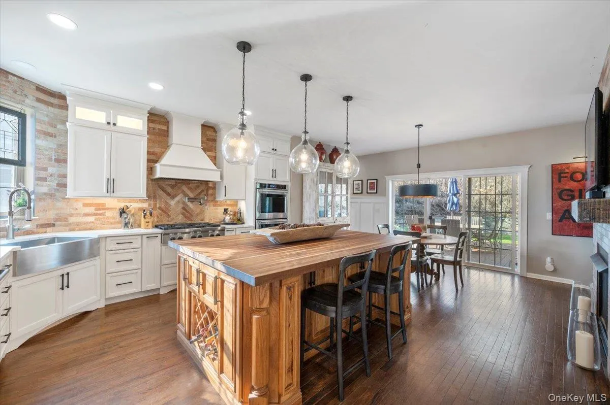 Kitchen featuring a breakfast bar area, glass insert cabinets, pendant lighting, dark wood-style floors, and recessed lighting Kitchen featuring a breakfast bar area, glass insert cabinets, pendant lighting, dark wood-style floors, and recessed lighting