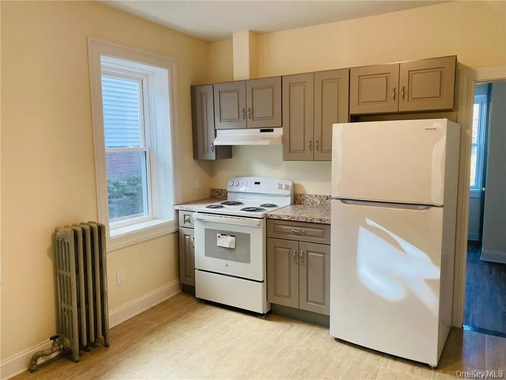 Kitchen featuring white appliances, gray cabinetry, and radiator Kitchen featuring white appliances, gray cabinetry, and radiator