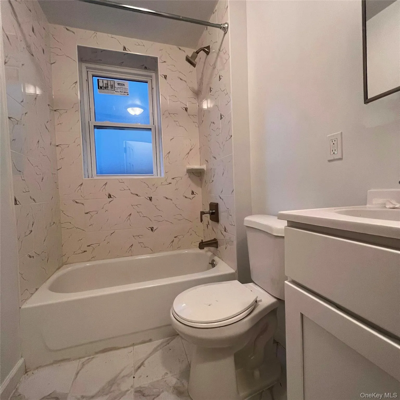 Full bathroom featuring vanity, bathing tub / shower combination, and marble look tile flooring Full bathroom featuring vanity, bathing tub / shower combination, and marble look tile flooring