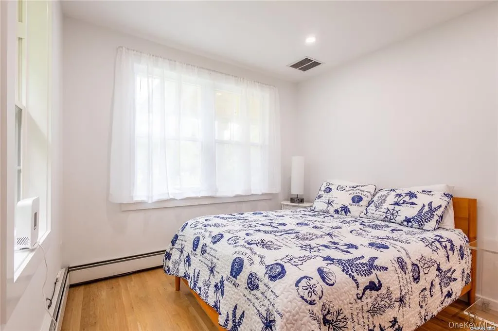 Bedroom featuring wood finished floors and a baseboard heating unit Bedroom featuring wood finished floors and a baseboard heating unit