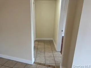 Hall featuring light tile patterned floors and baseboards Hall featuring light tile patterned floors and baseboards
