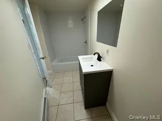 Bathroom with shower / bathtub combination, tile patterned flooring, baseboards, and vanity Bathroom with shower / bathtub combination, tile patterned flooring, baseboards, and vanity