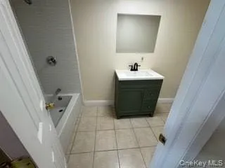 Bathroom with tile patterned flooring, shower / tub combination, vanity, and baseboards Bathroom with tile patterned flooring, shower / tub combination, vanity, and baseboards